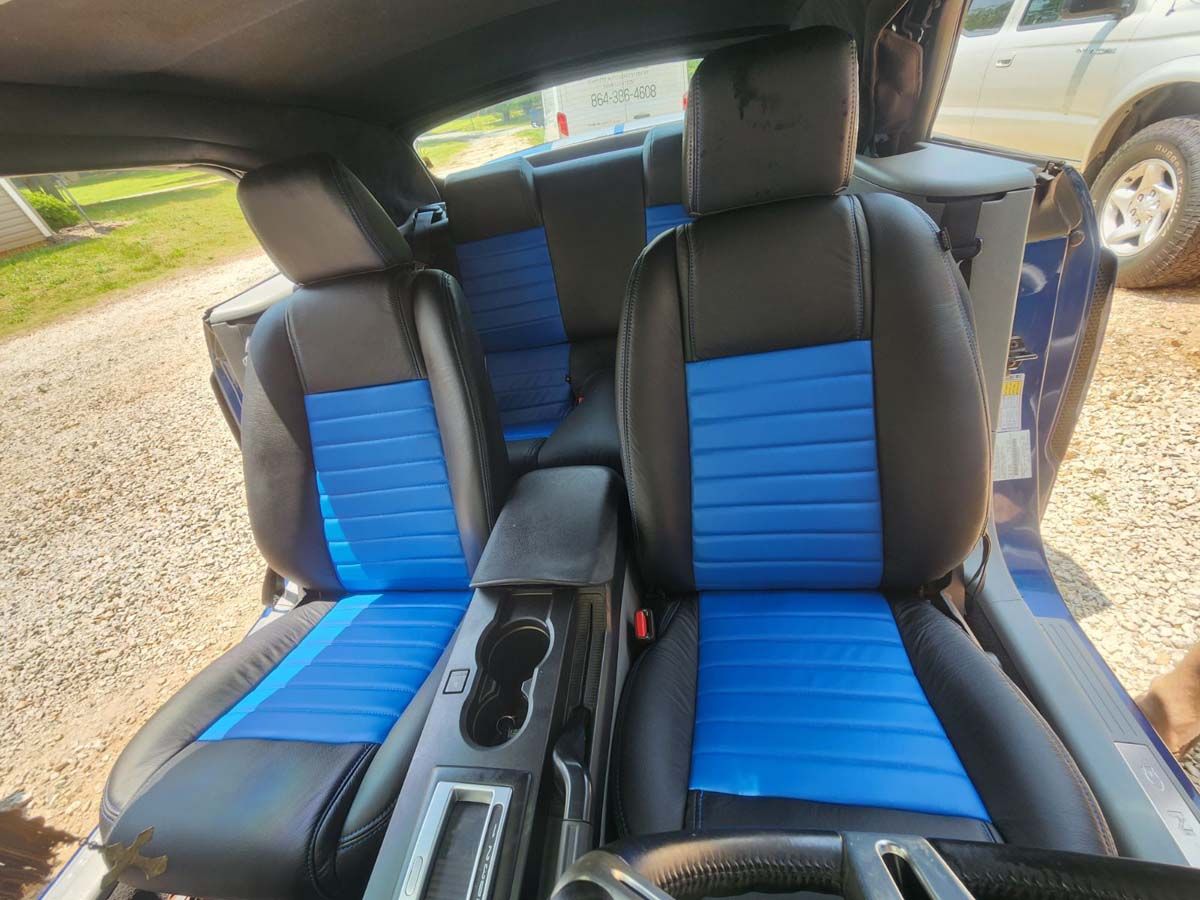 Blue and black car interior with blue ribbed seat inserts. Cup holders and gear shift visible.