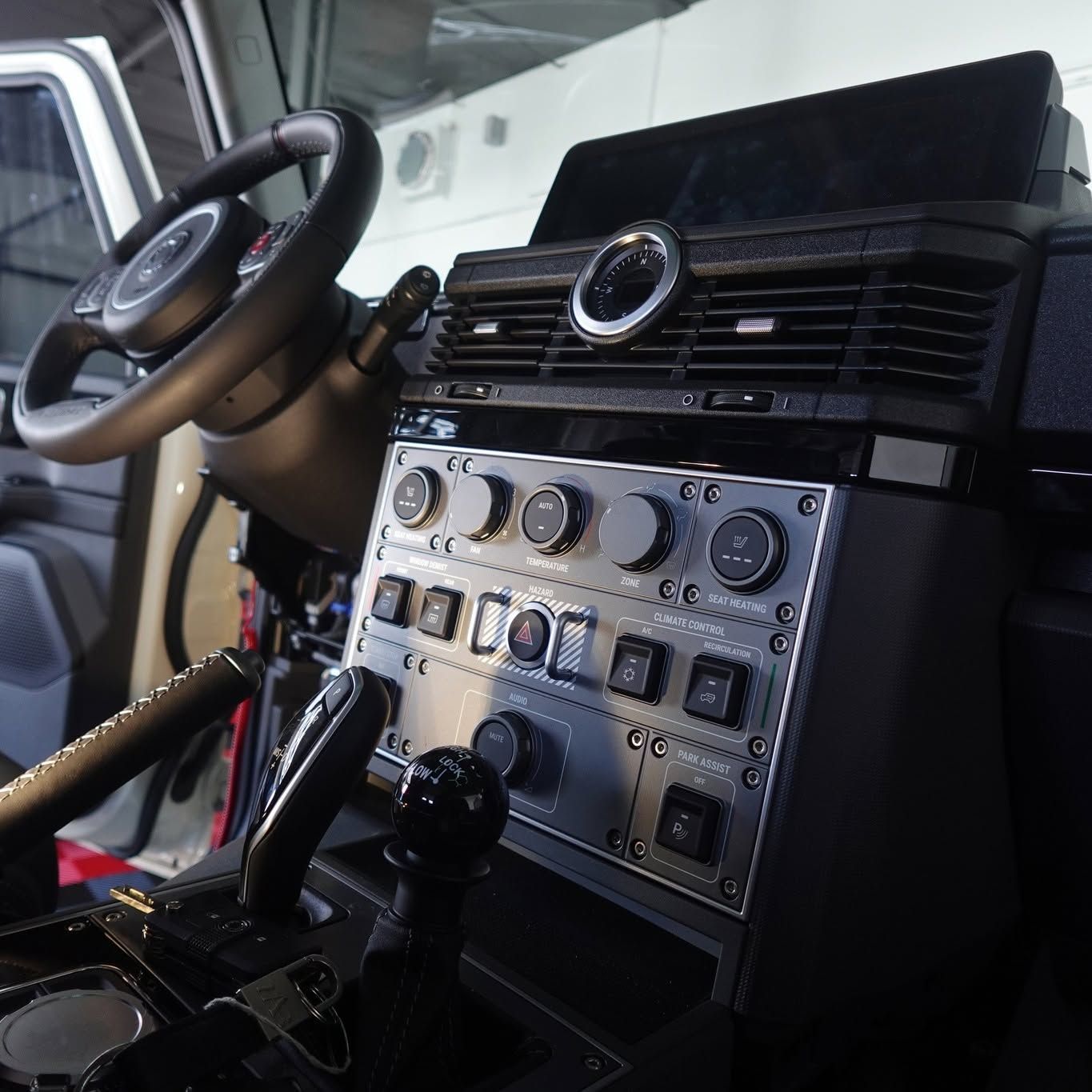 Car dashboard with steering wheel and radio controls, viewed from the driver’s seat.