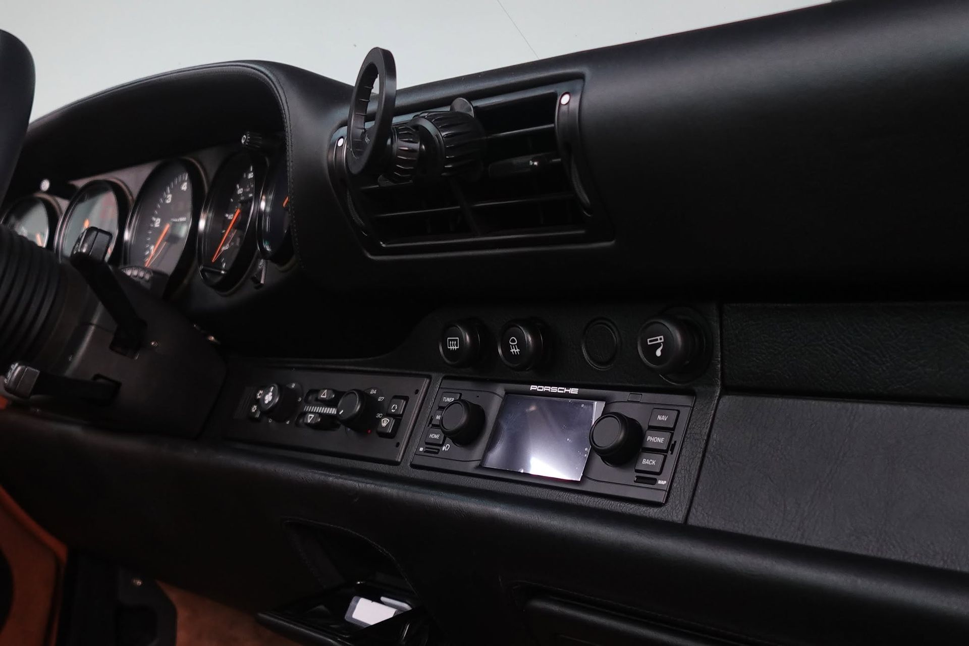 Car dashboard and center console with gauges, vents, and a touchscreen in a dark interior