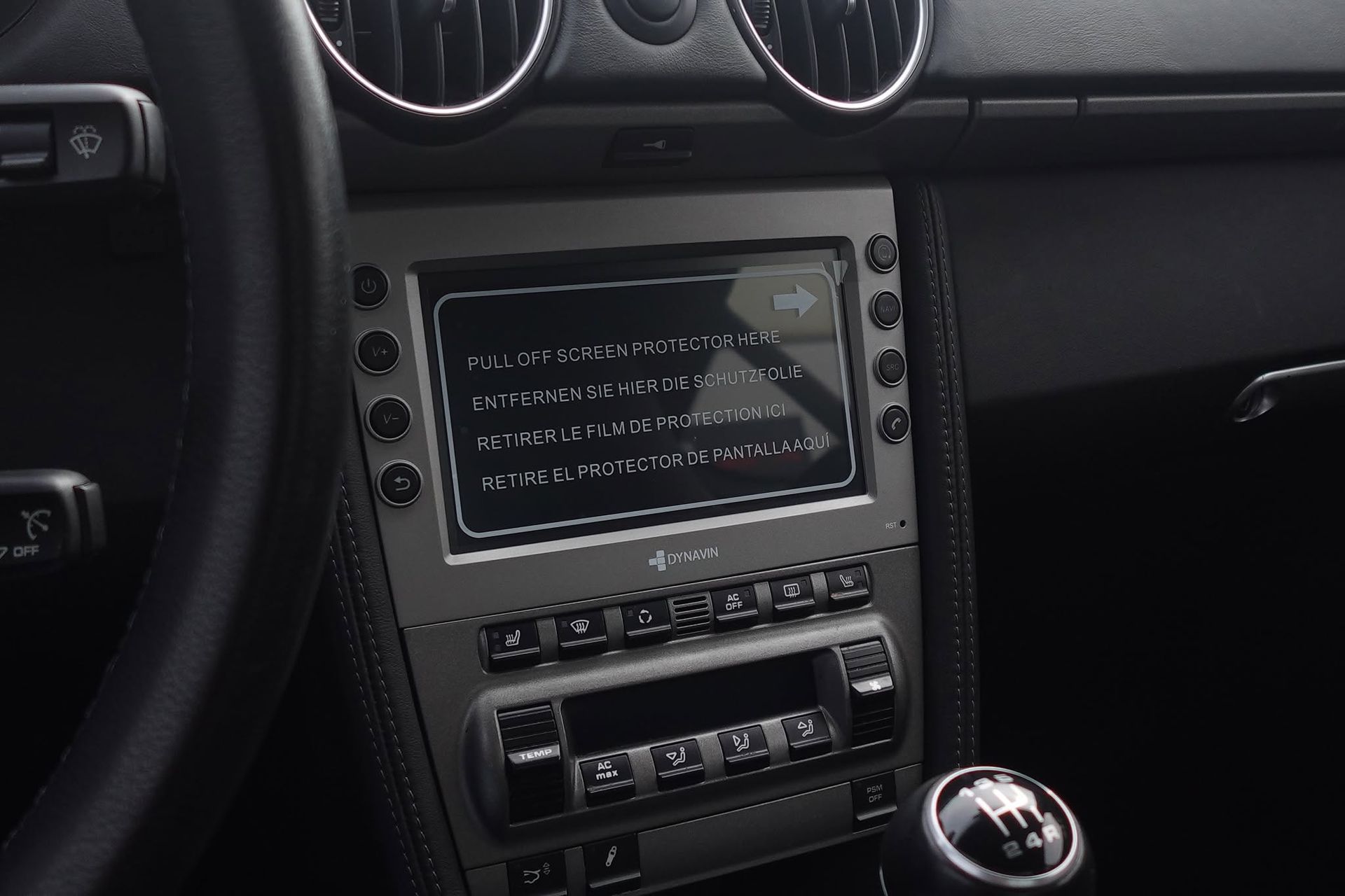 Car dashboard center console with touchscreen display and manual gear shift in a black interior