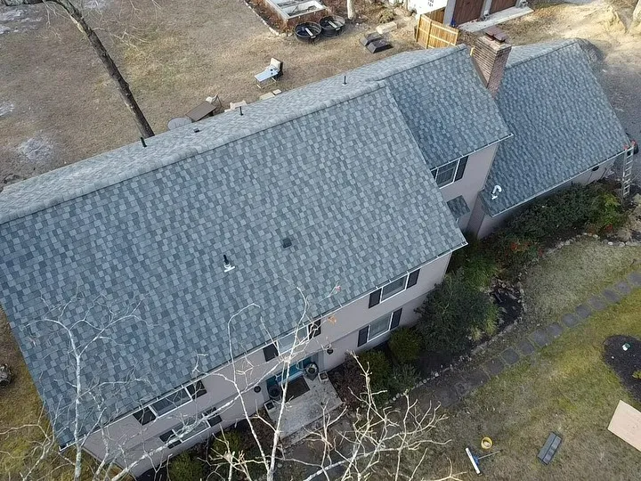 Aerial view of a gray-roofed house with landscaping and a patchy lawn.