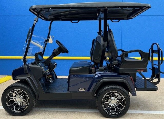 A blue golf cart is parked in front of a blue wall.
