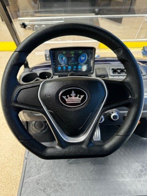 The steering wheel of a golf cart has a crown on it.
