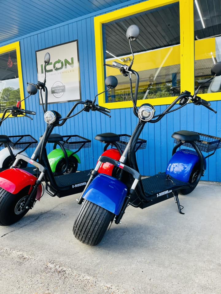 Three scooters are parked in front of a building that says icon
