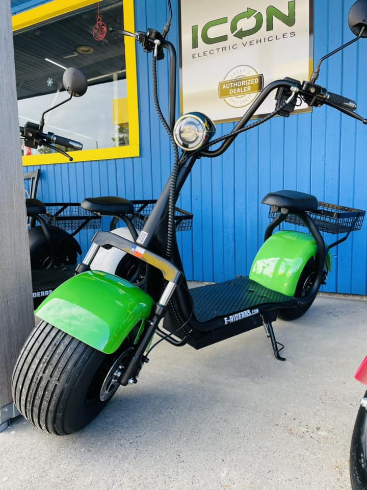 A green scooter is parked in front of a blue building.