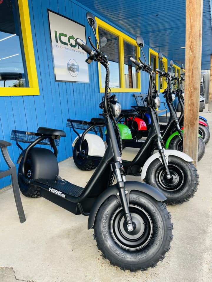 A row of electric scooters are parked in front of a building.