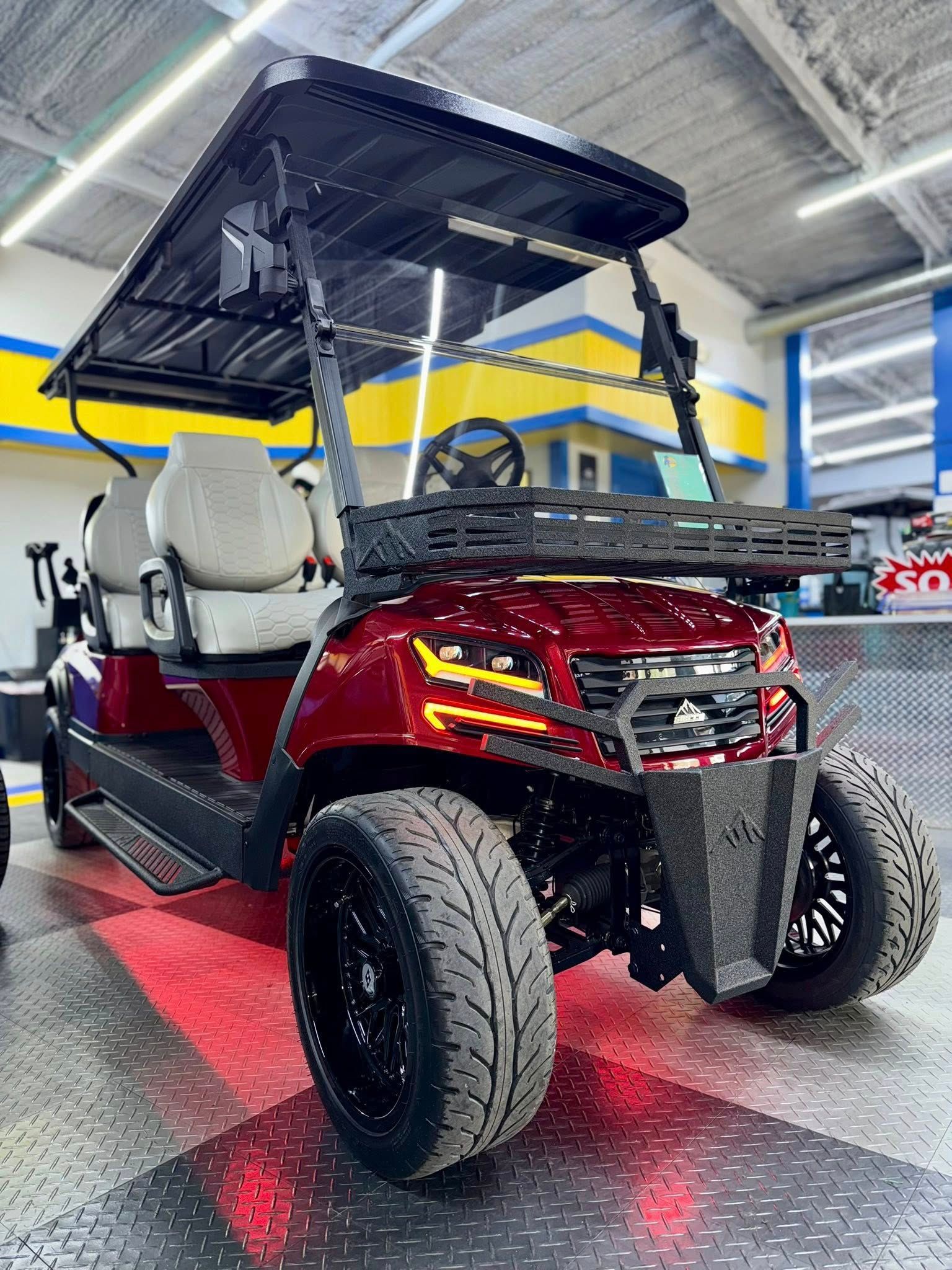 Red golf cart with black accents, black wheels, and a rack, parked inside a garage.