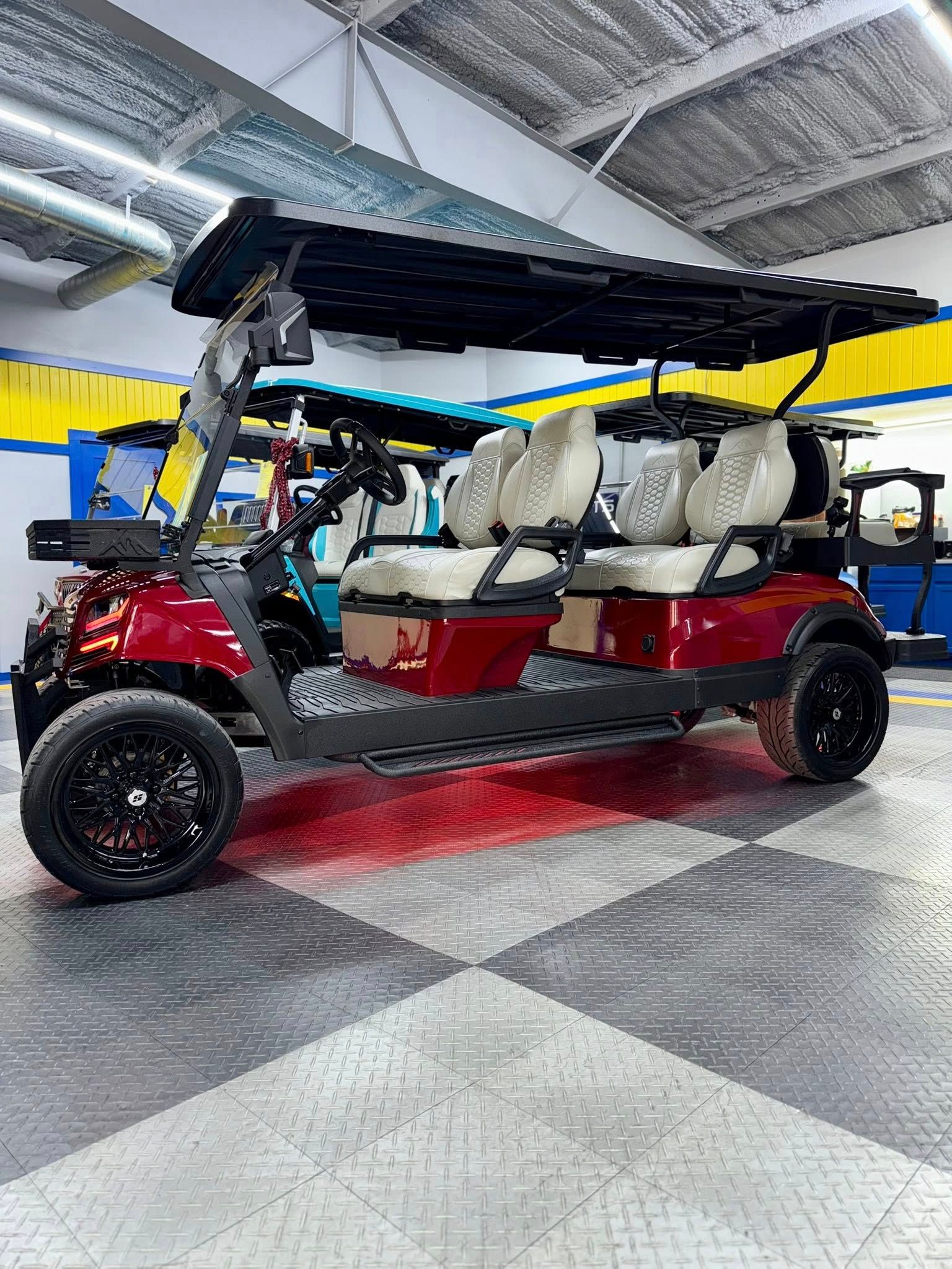 Red golf cart with black wheels and canopy, parked inside on patterned flooring.