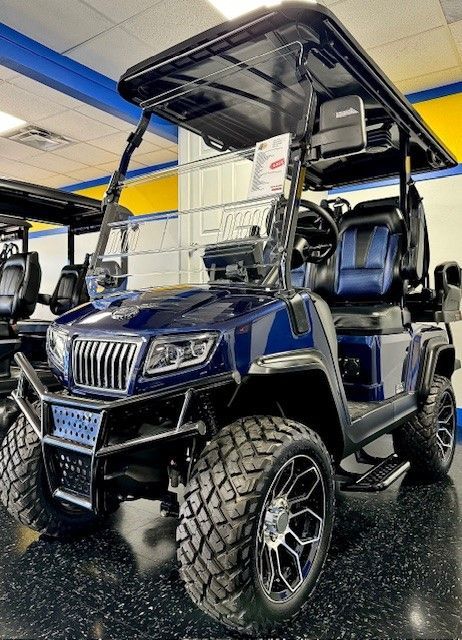 Dark blue golf cart with black roof, large tires, and chrome accents inside a showroom.