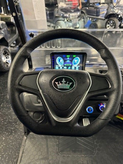 Black steering wheel with silver accents and digital display in a golf cart. The dashboard has a crown logo.
