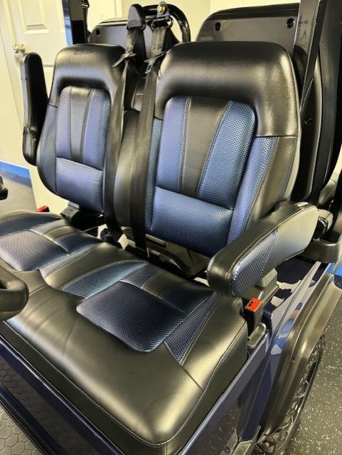 Two-tone blue and black seats in a mobility scooter, with seatbelts and armrests.