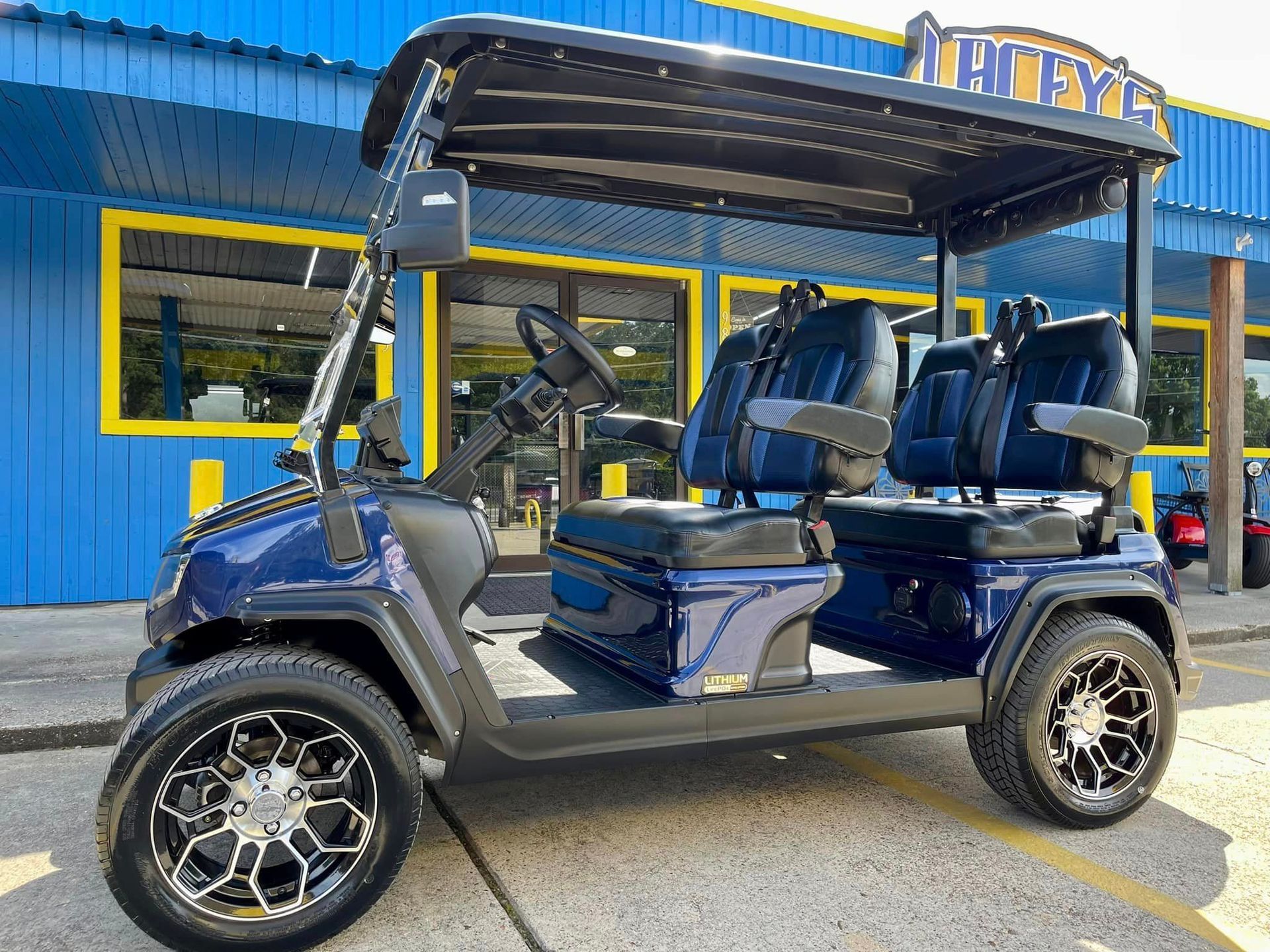 A blue golf cart is parked in front of a blue building.
