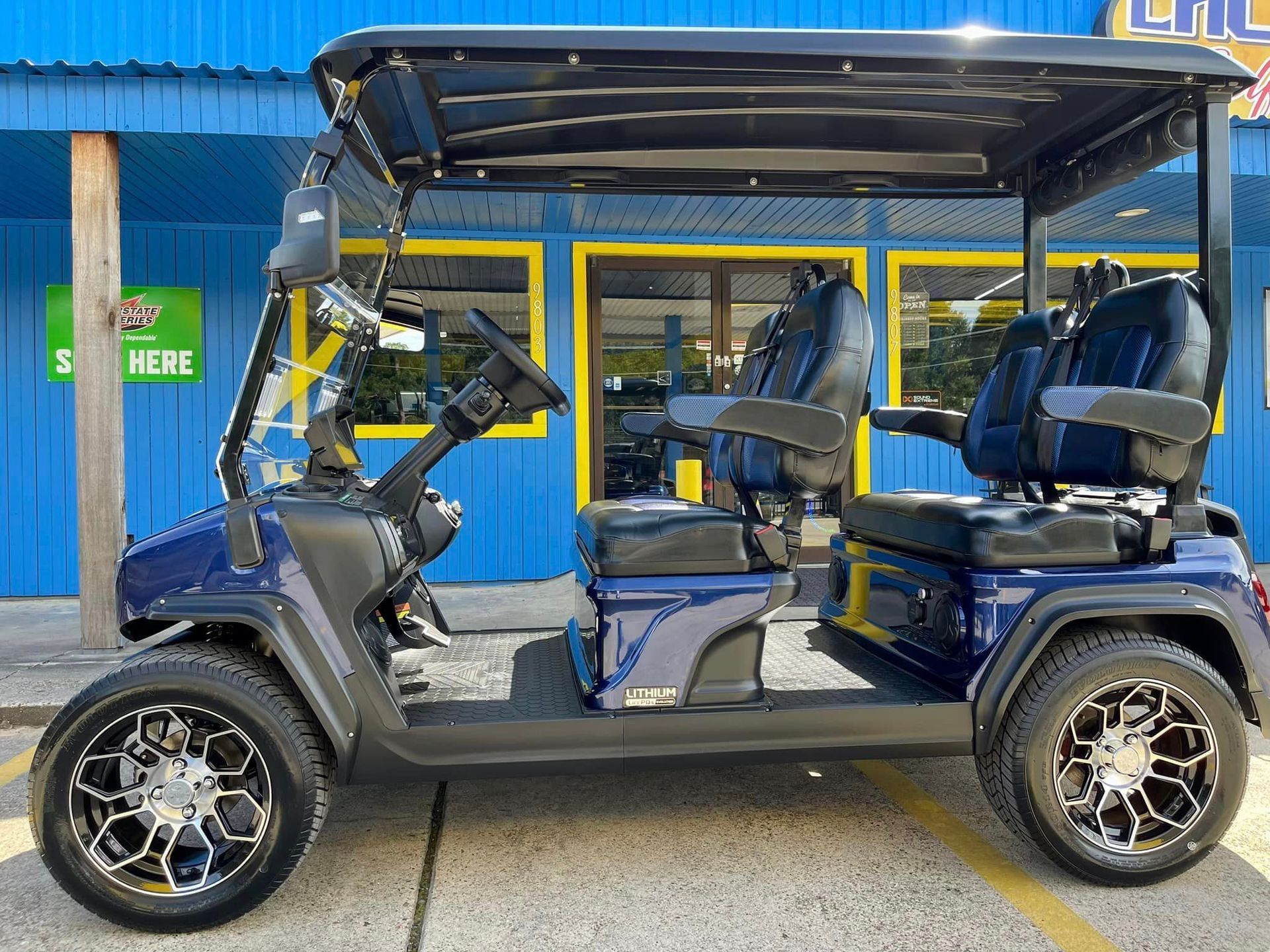 A blue golf cart is parked in front of a blue building.