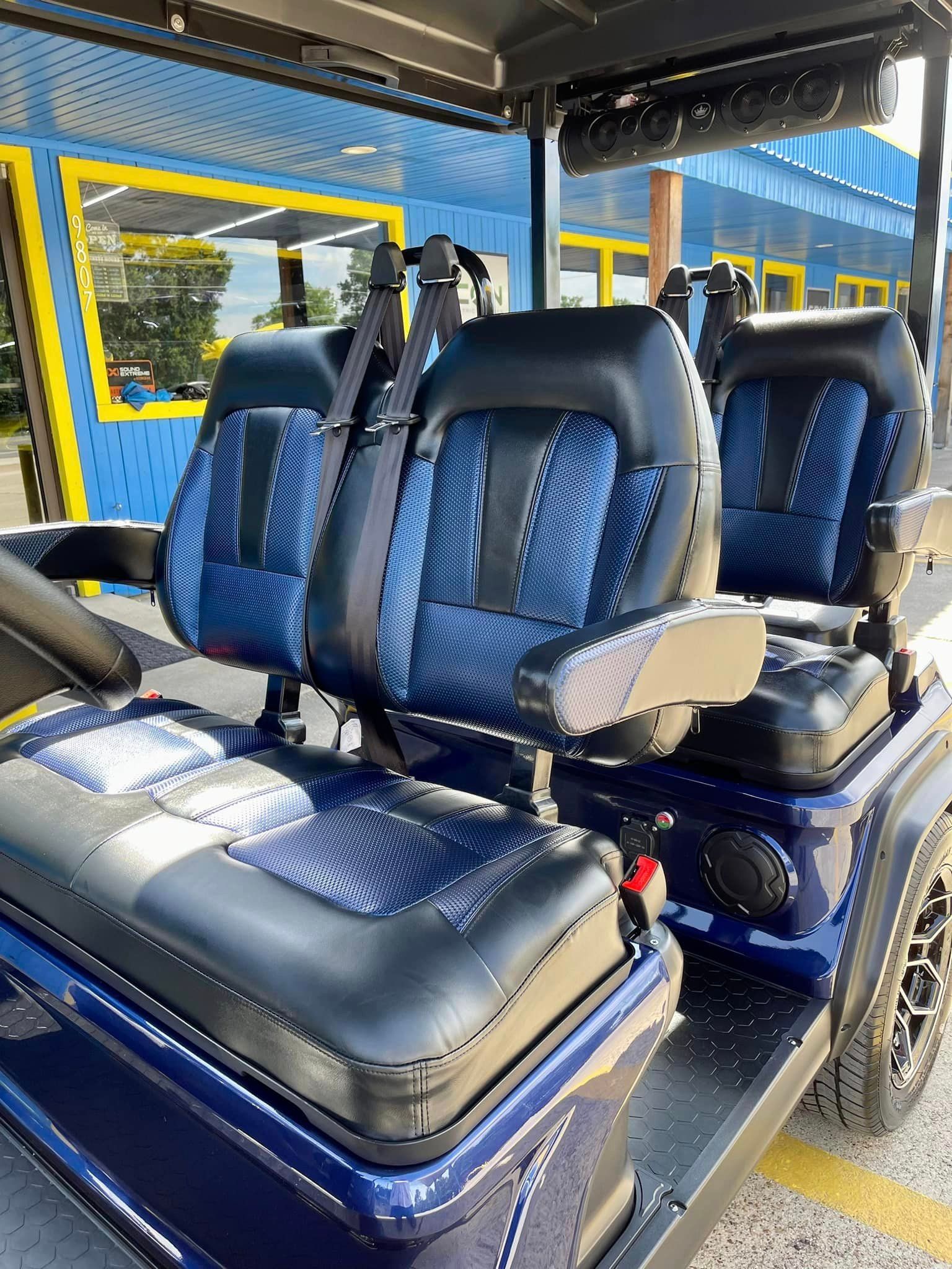 A golf cart with blue and black seats is parked in a parking lot.