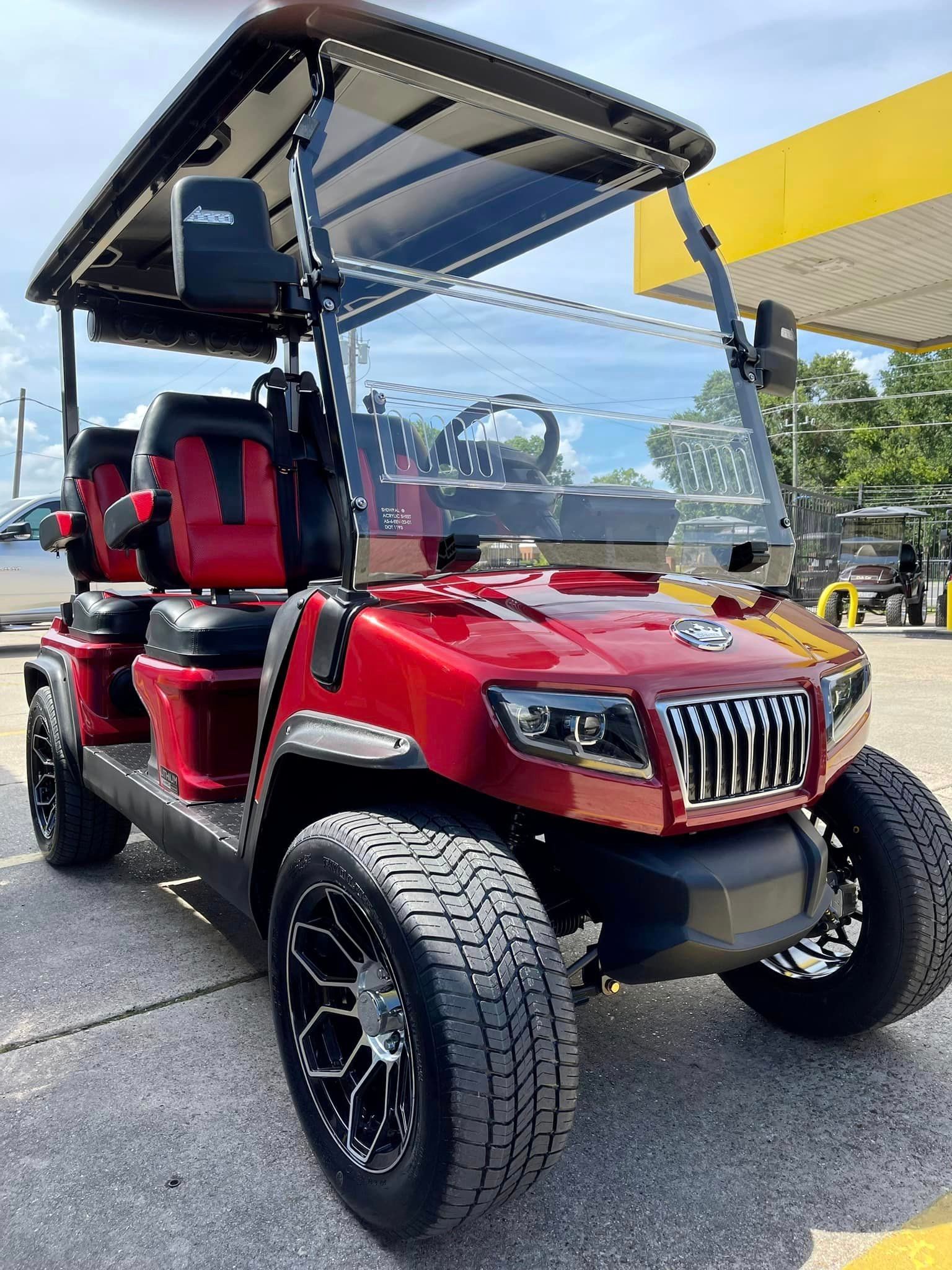 A red golf cart is parked in a parking lot in front of a gas station.
