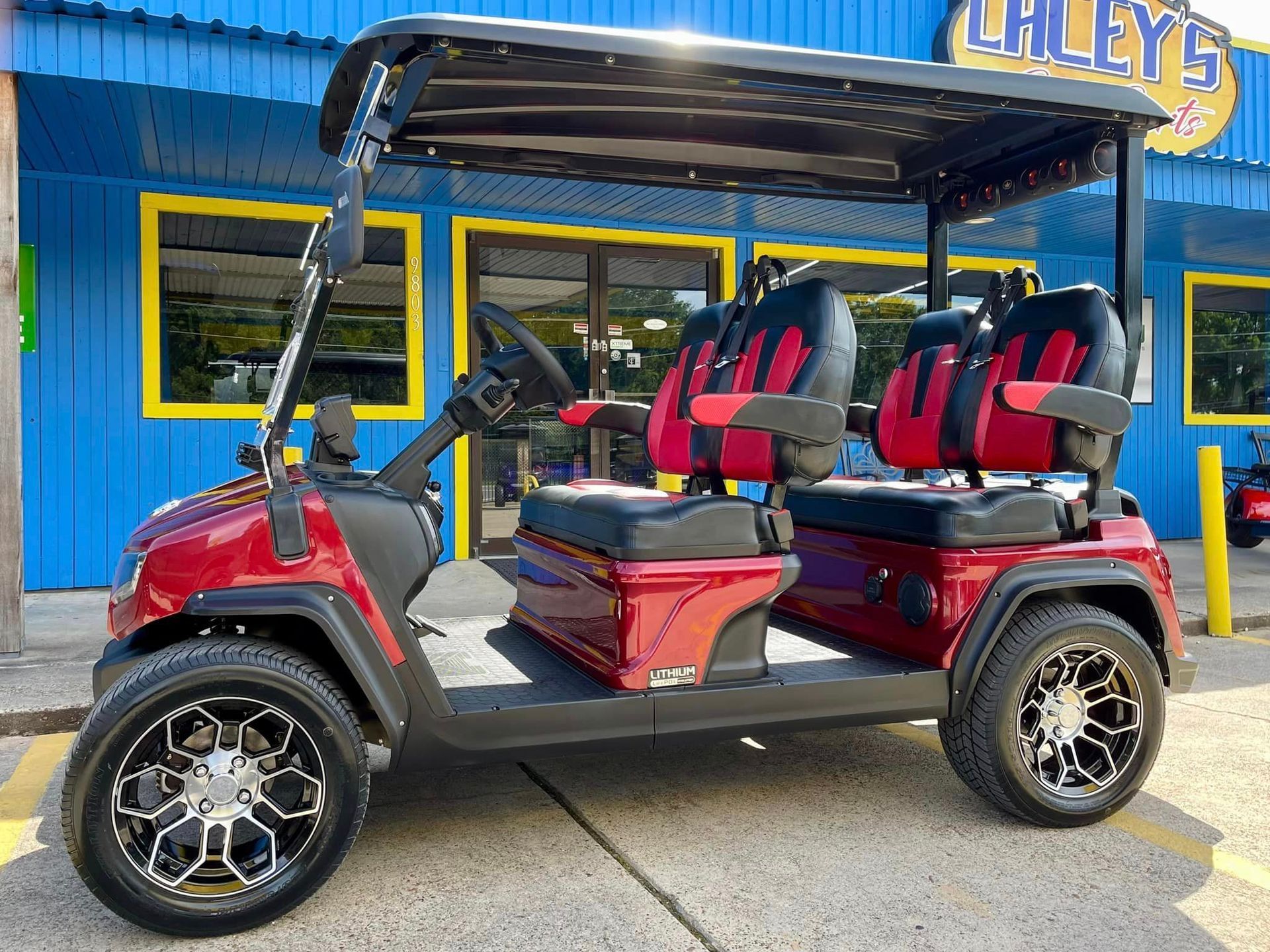A red golf cart is parked in front of a blue building.