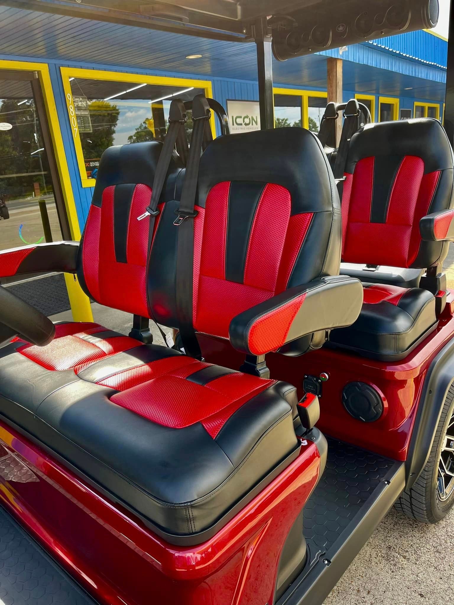 The inside of a golf cart with red and black seats