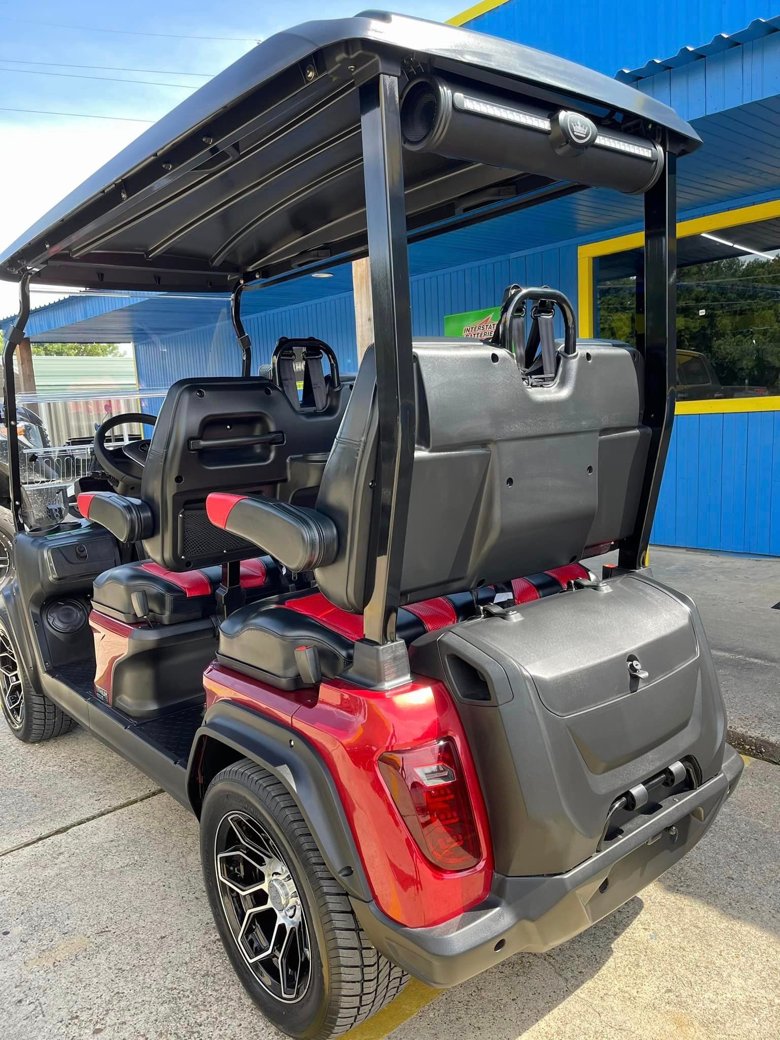 A red golf cart is parked in front of a blue building.