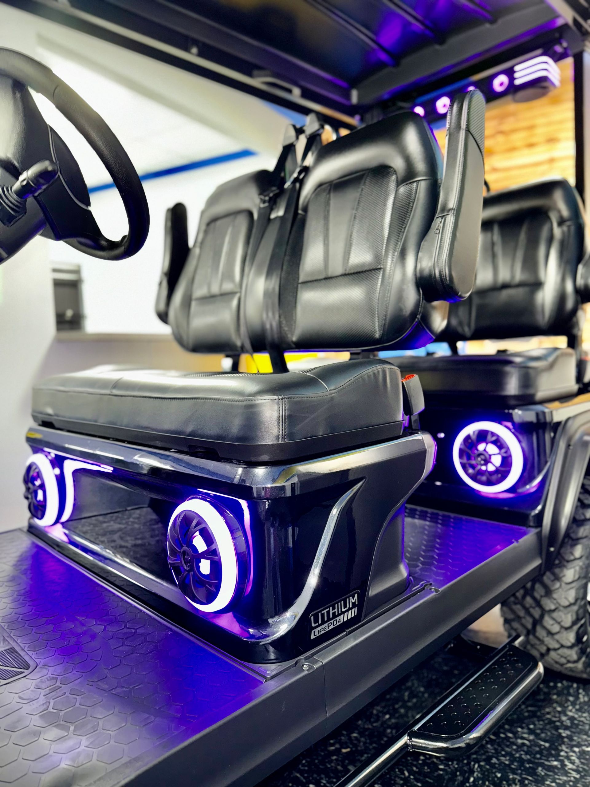 The seats of a golf cart are lit up with purple lights.