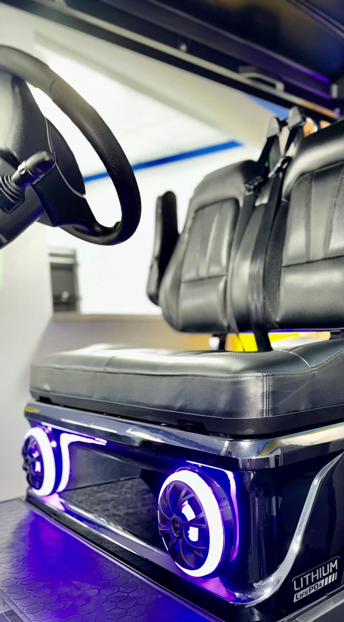 A close up of a car seat with a steering wheel in the background.