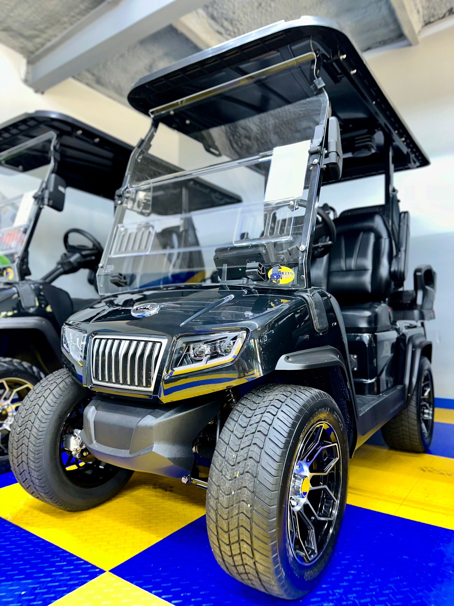 A black golf cart is parked on a blue and yellow checkered floor.