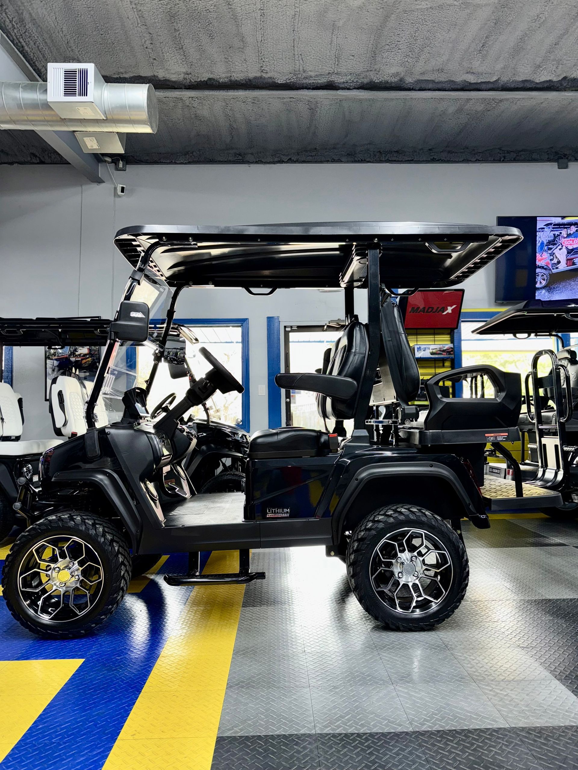 A black golf cart is parked in a garage.