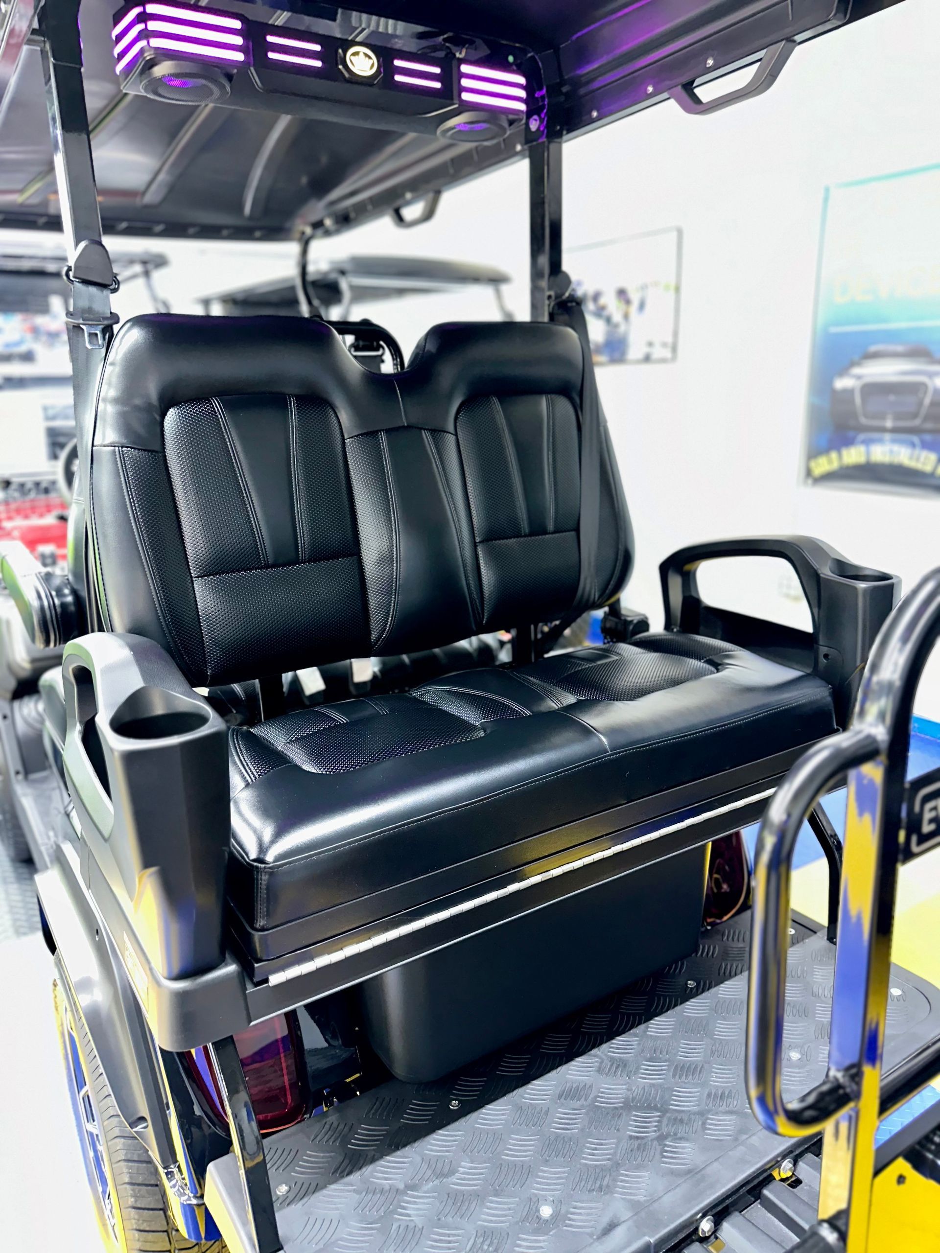 The back seat of a golf cart with a black seat and purple lights.