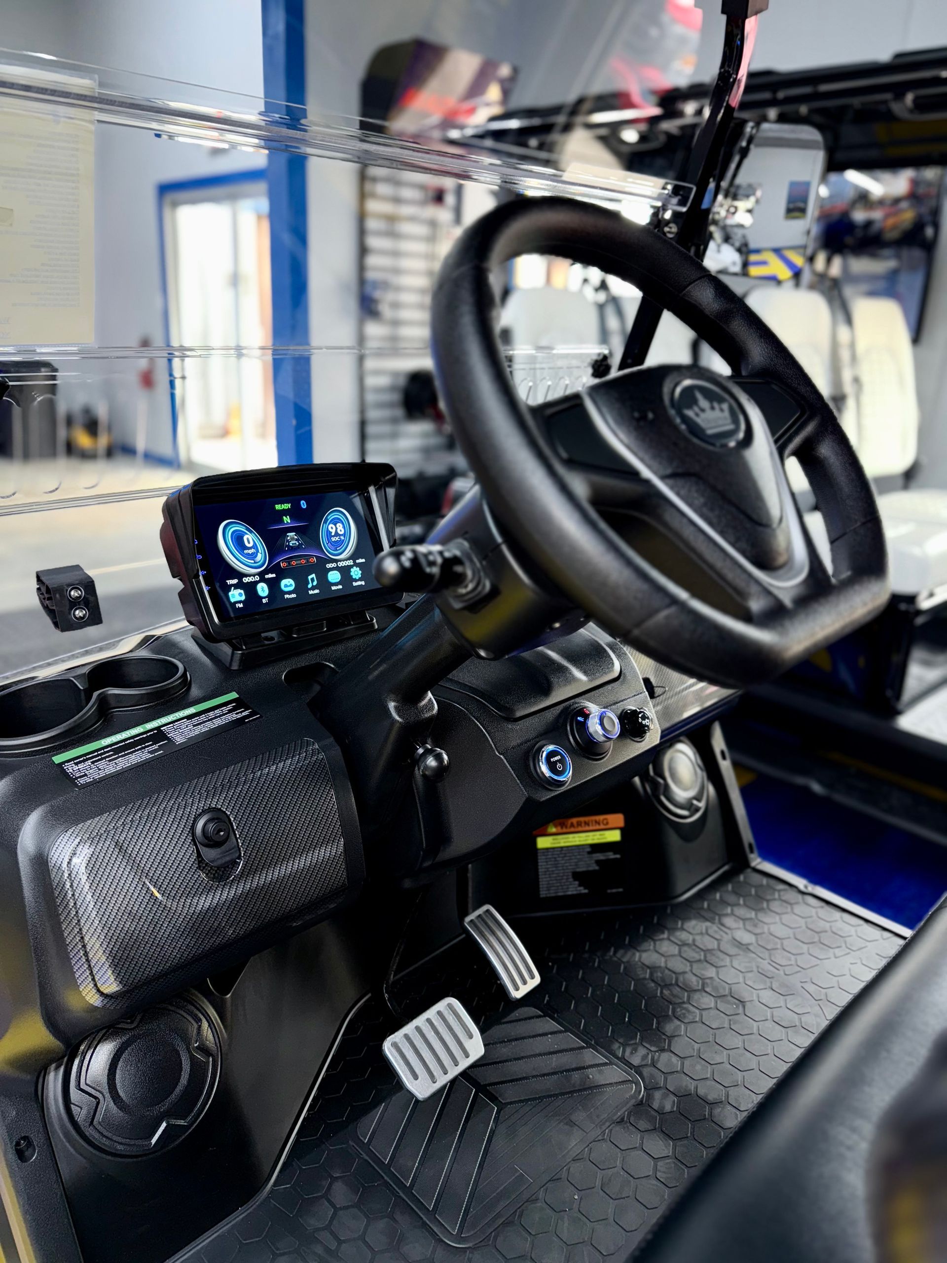 The inside of a golf cart with a steering wheel and dashboard.