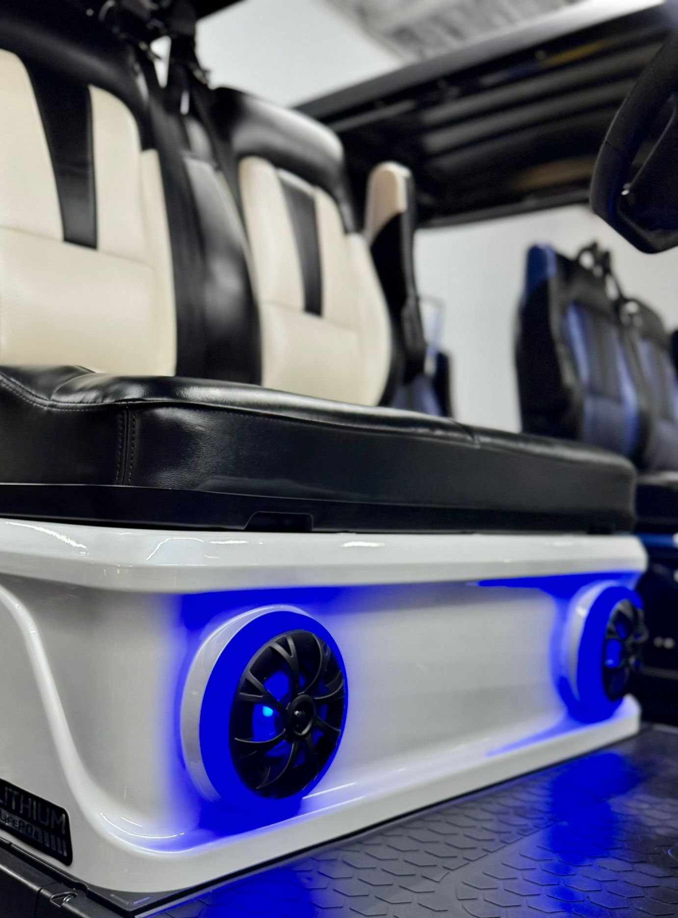 The back of a golf cart with speakers and blue lights.