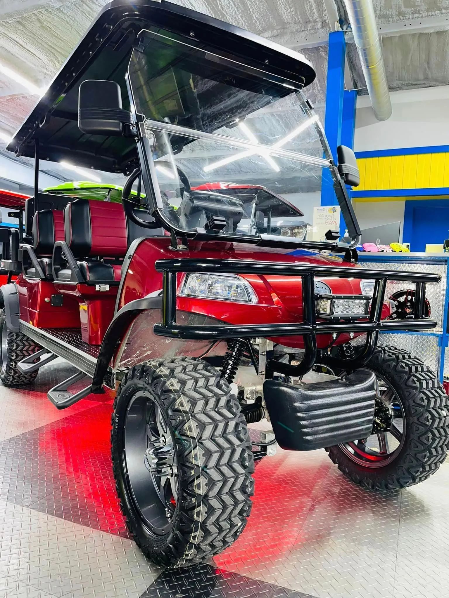 A red golf cart is parked in a garage.