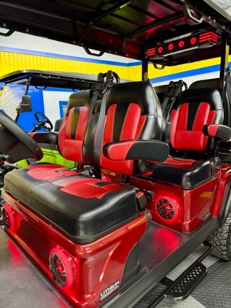 A red golf cart with black seats is parked in a garage.