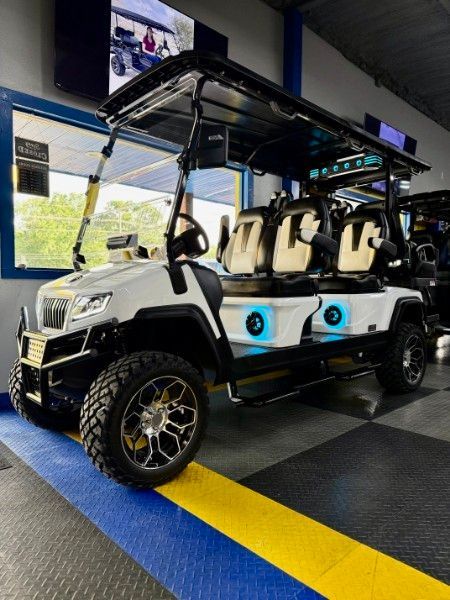 A white golf cart is parked in a garage.