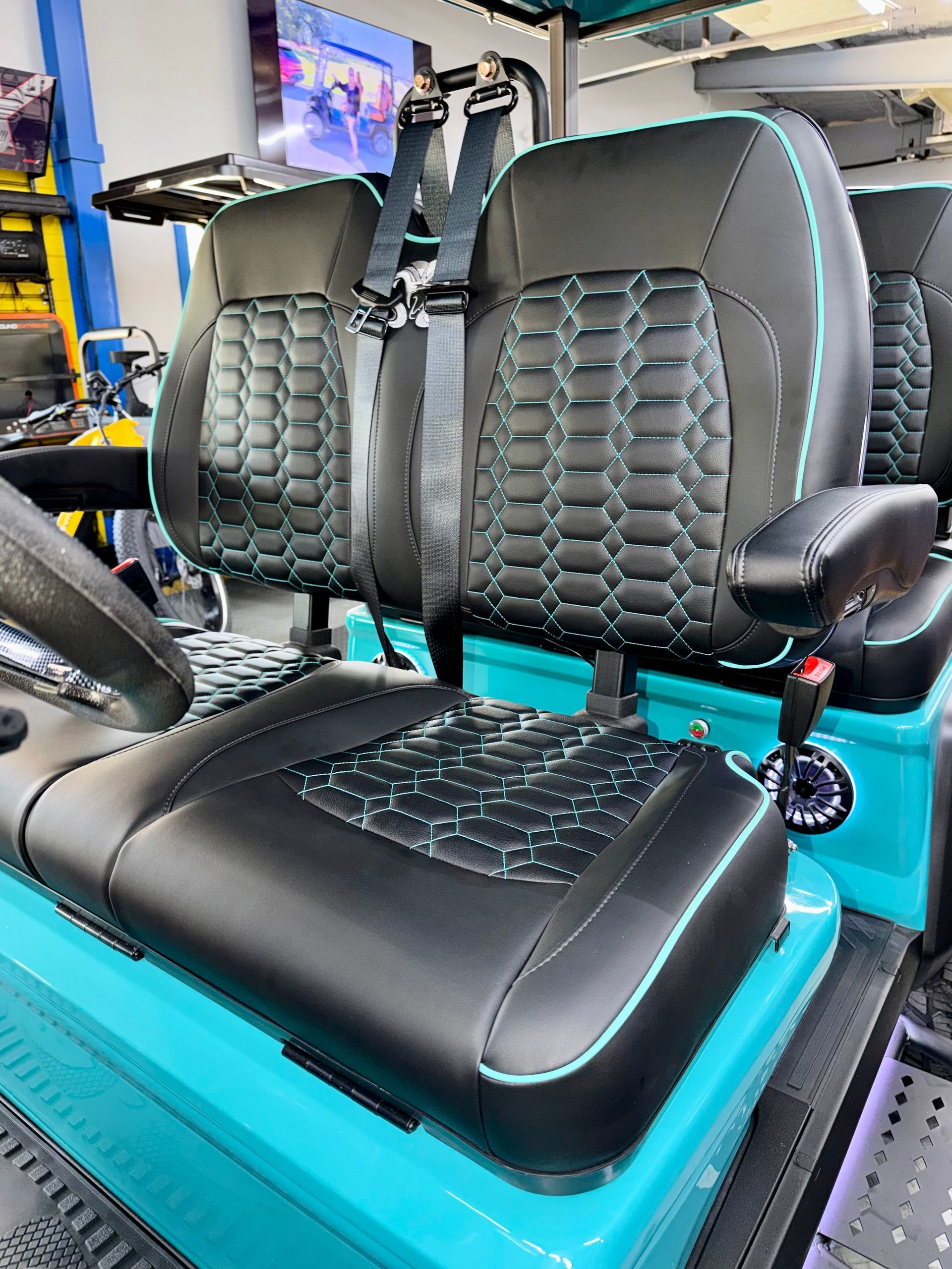 Two black quilted car seats with turquoise base in a workshop setting