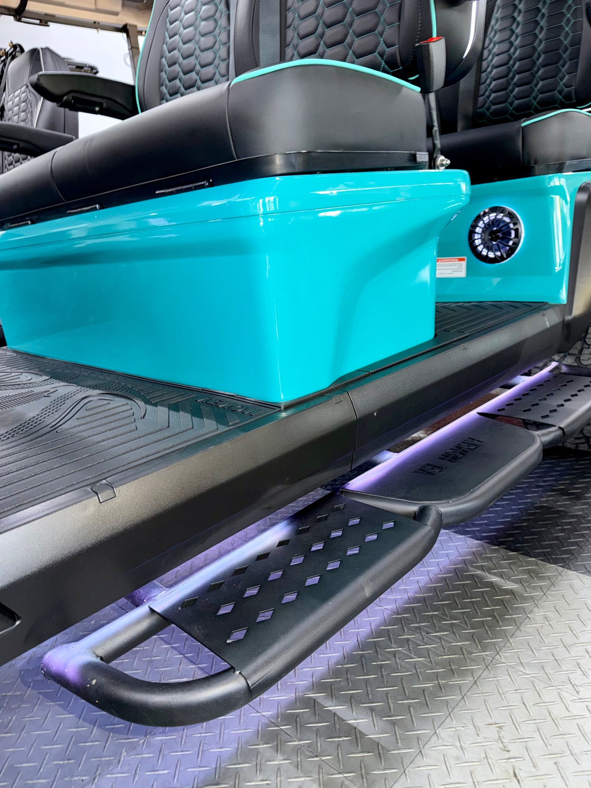 Turquoise car seat base with black step board and purple lighting inside a vehicle