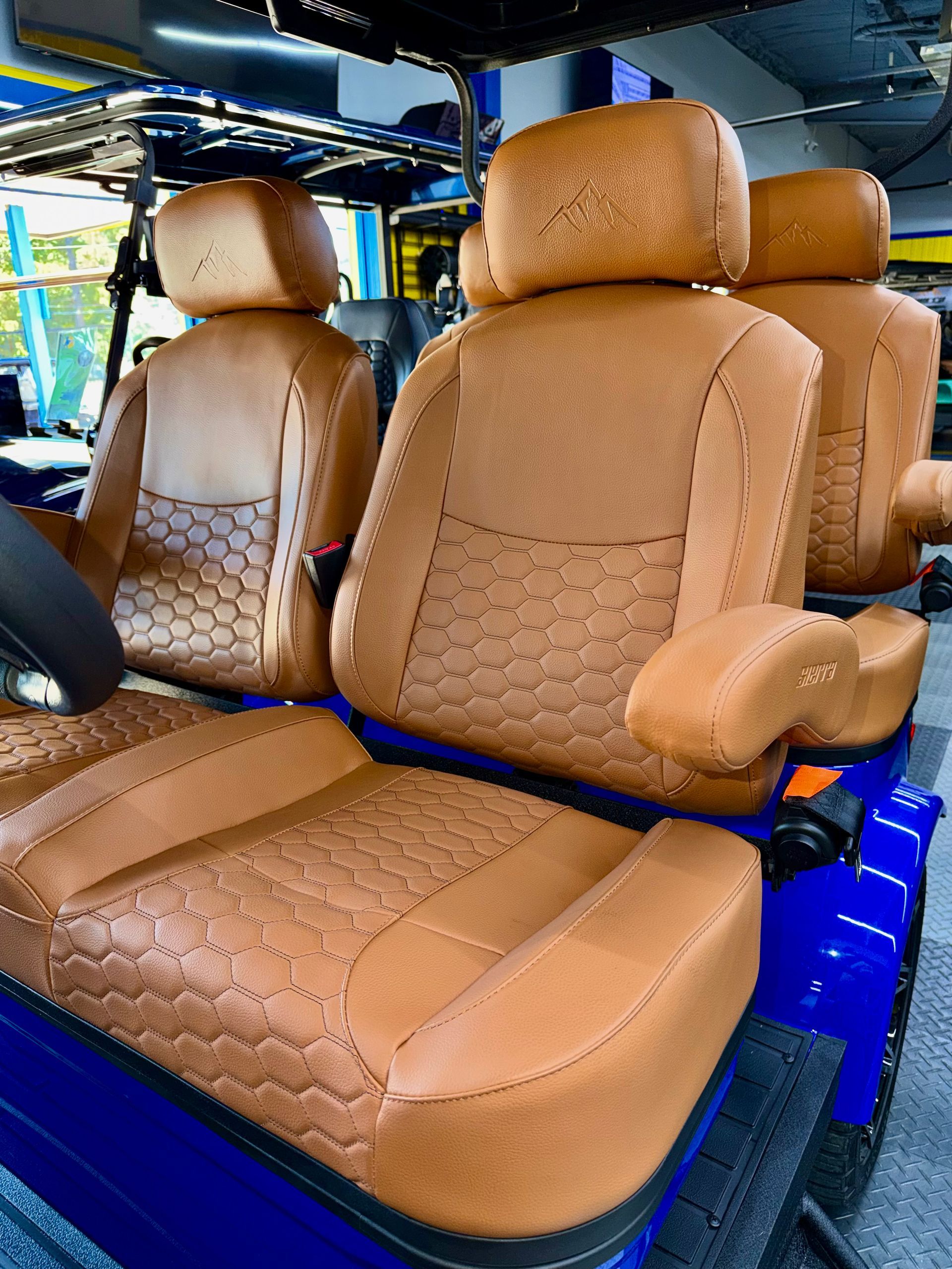 Tan leather car seats with quilted stitching in a vehicle interior, viewed from the back seat
