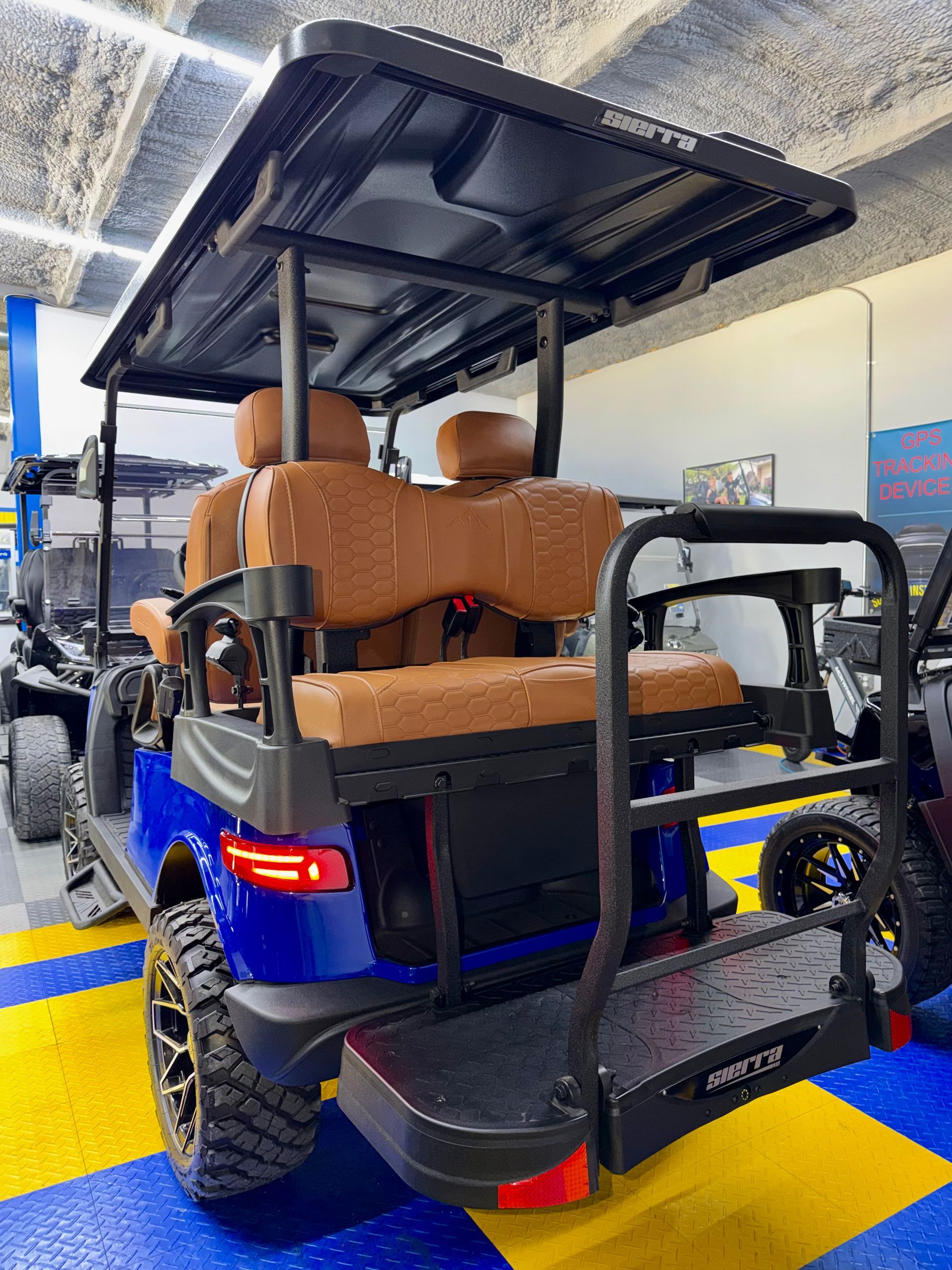Blue utility cart loaded with brown boxes in a brightly lit indoor warehouse aisle