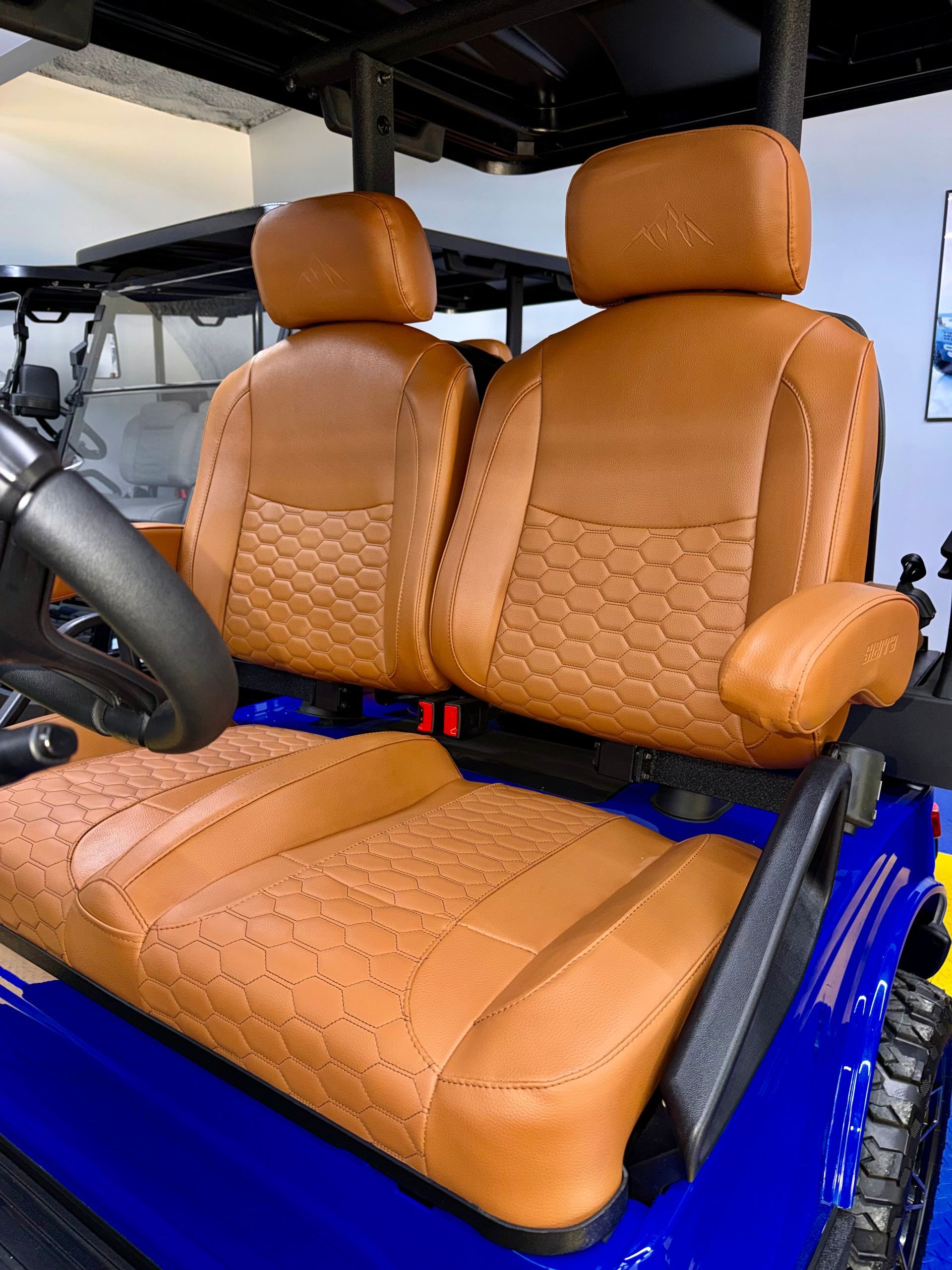 Blue off-road vehicle interior with tan leather bucket seats and black steering wheel