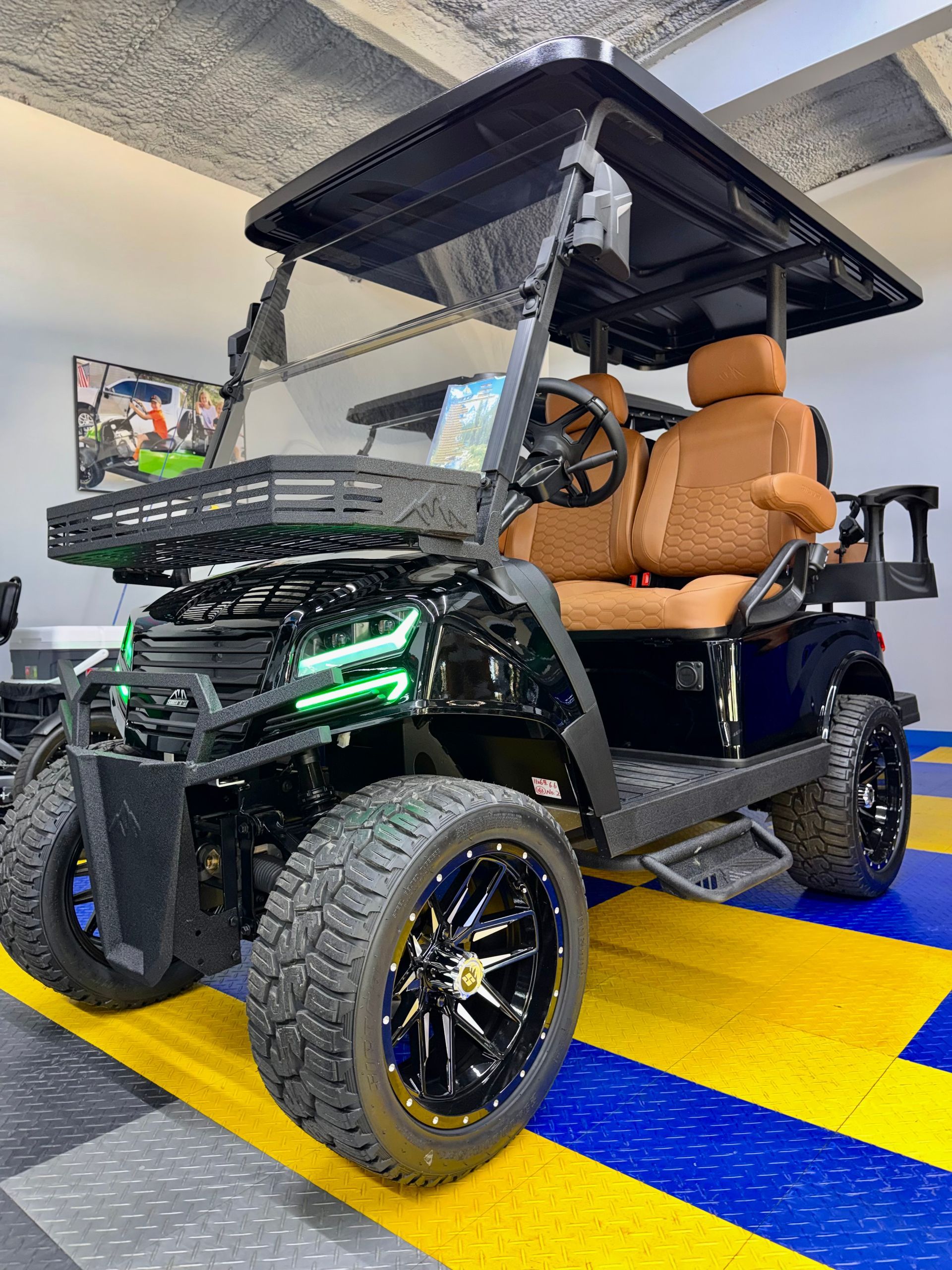 Custom black golf cart with tan seats and canopy, parked indoors on blue and yellow striped flooring.
