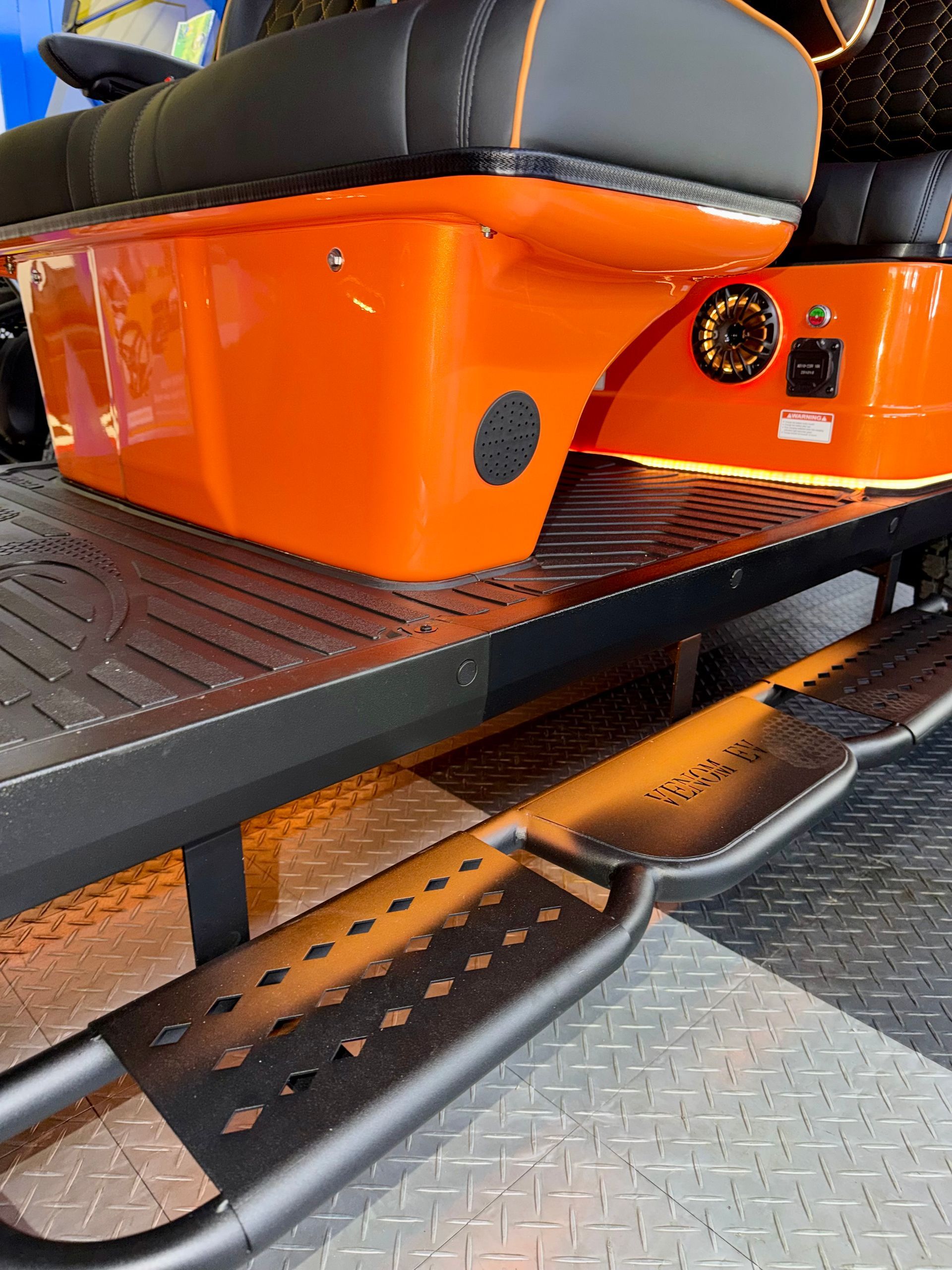 Orange off-road vehicle step and running board with black textured platforms and diamond-plate flooring.