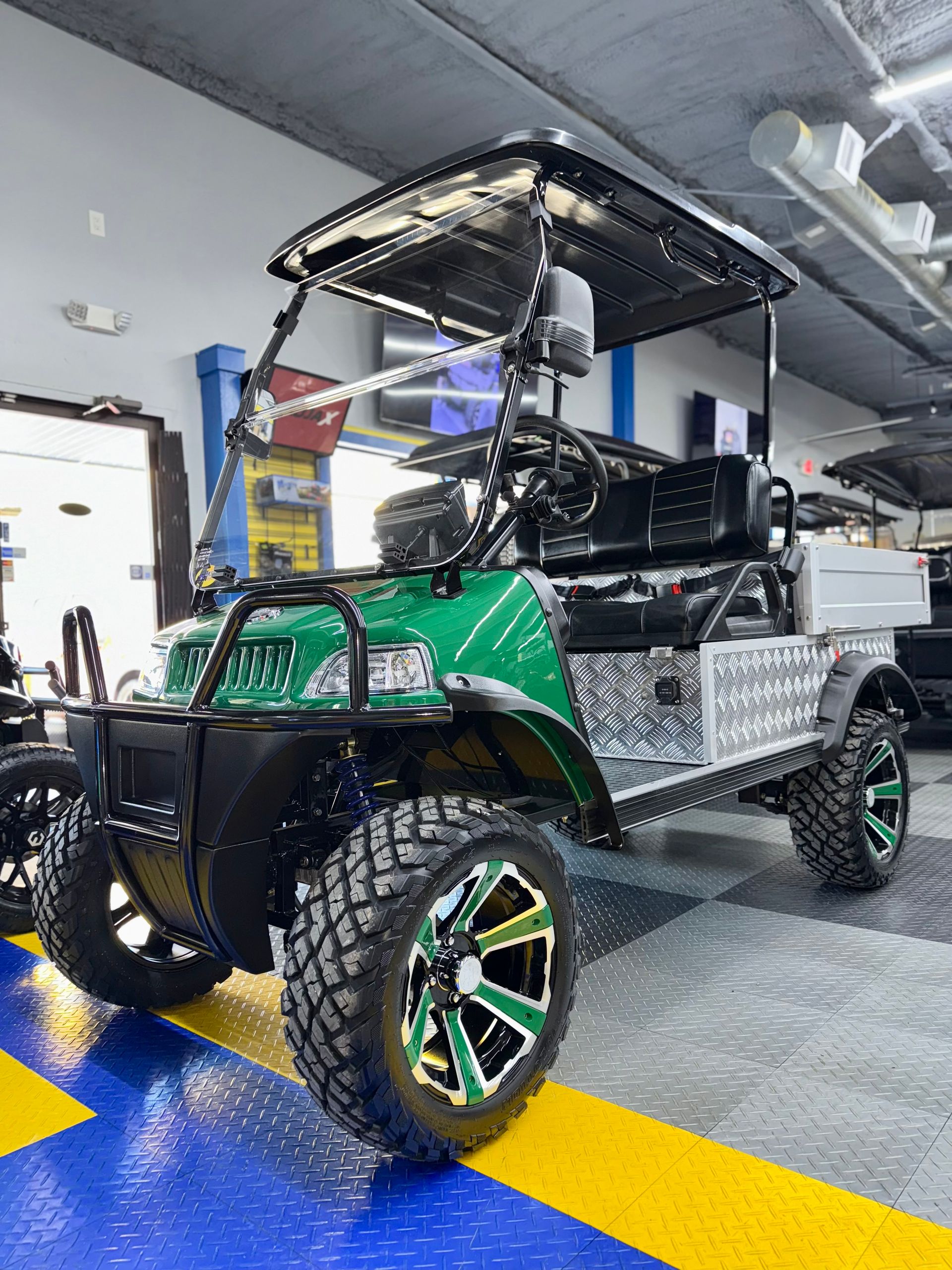 A green golf cart is parked in a garage.