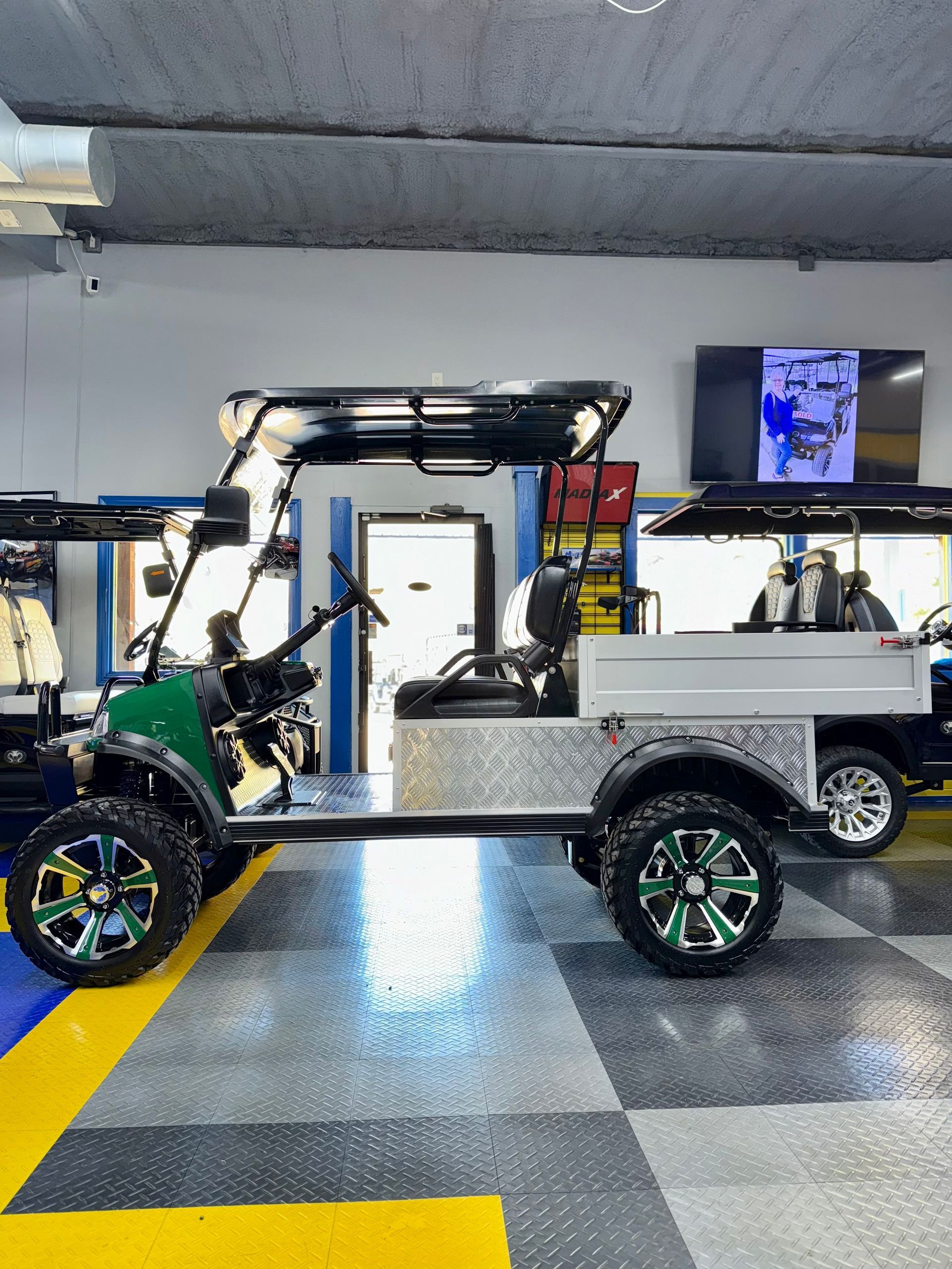 A green and white golf cart is parked in a garage.