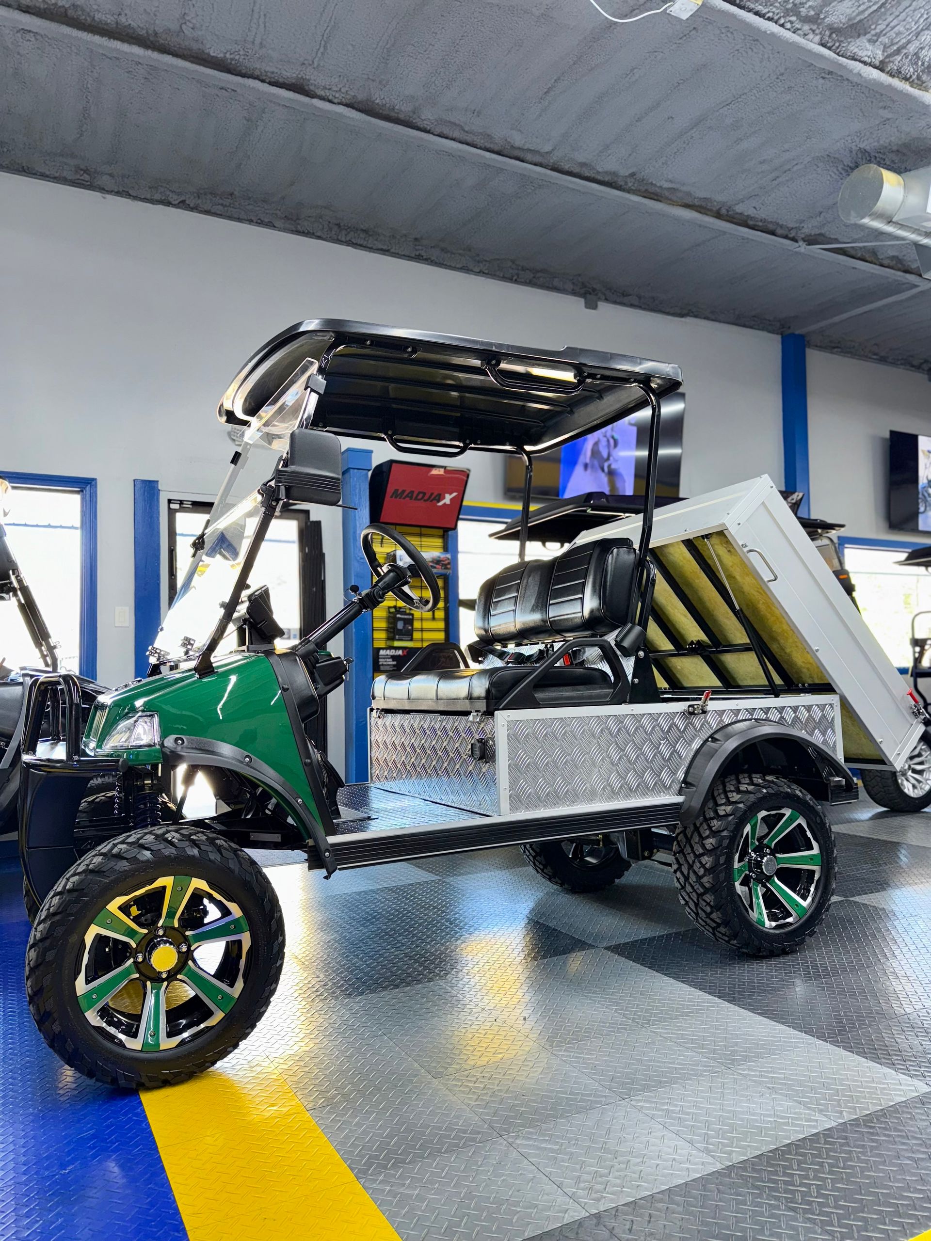 A green and white golf cart is parked in a garage.