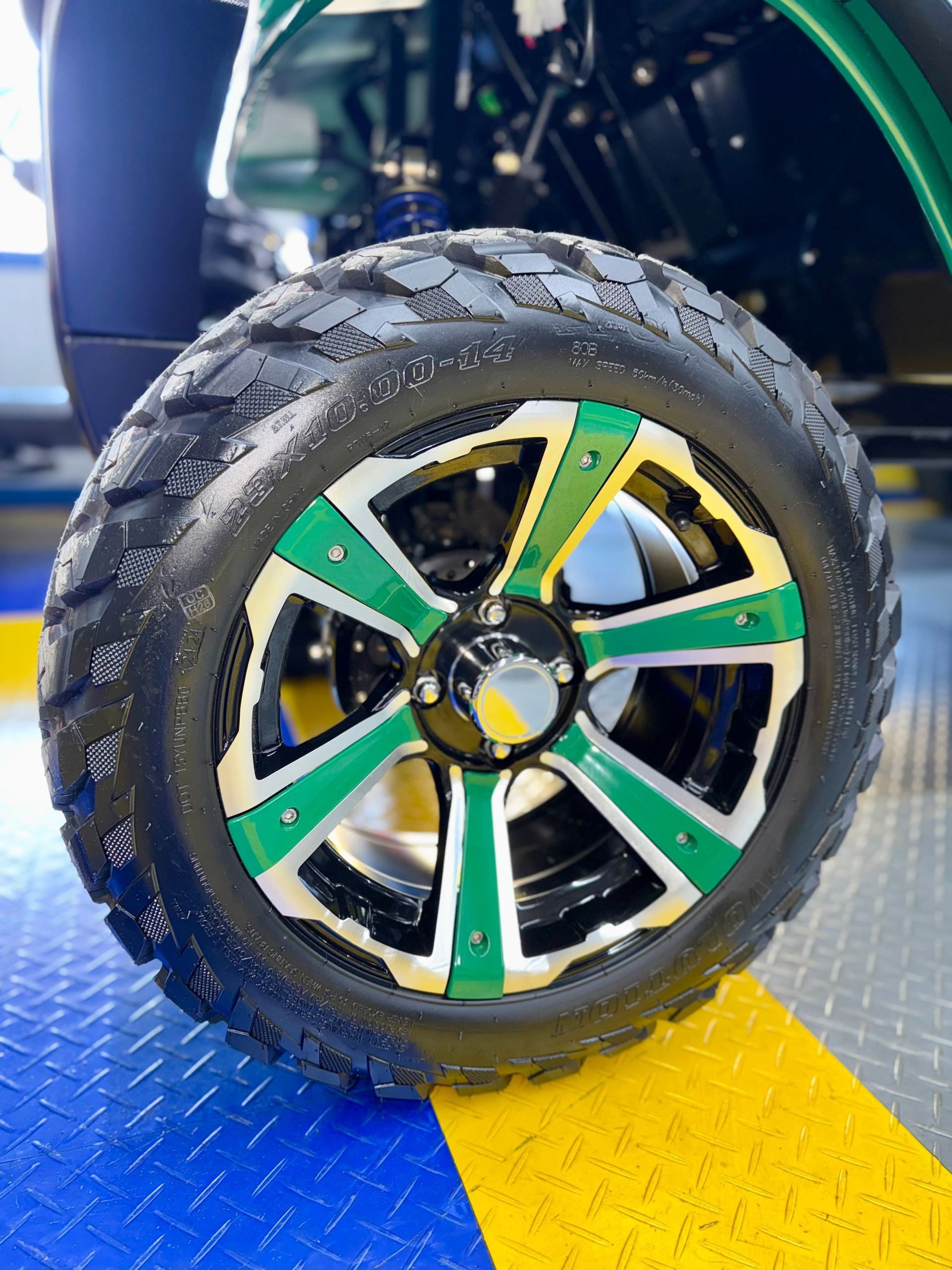 A close up of a green and white golf cart wheel.