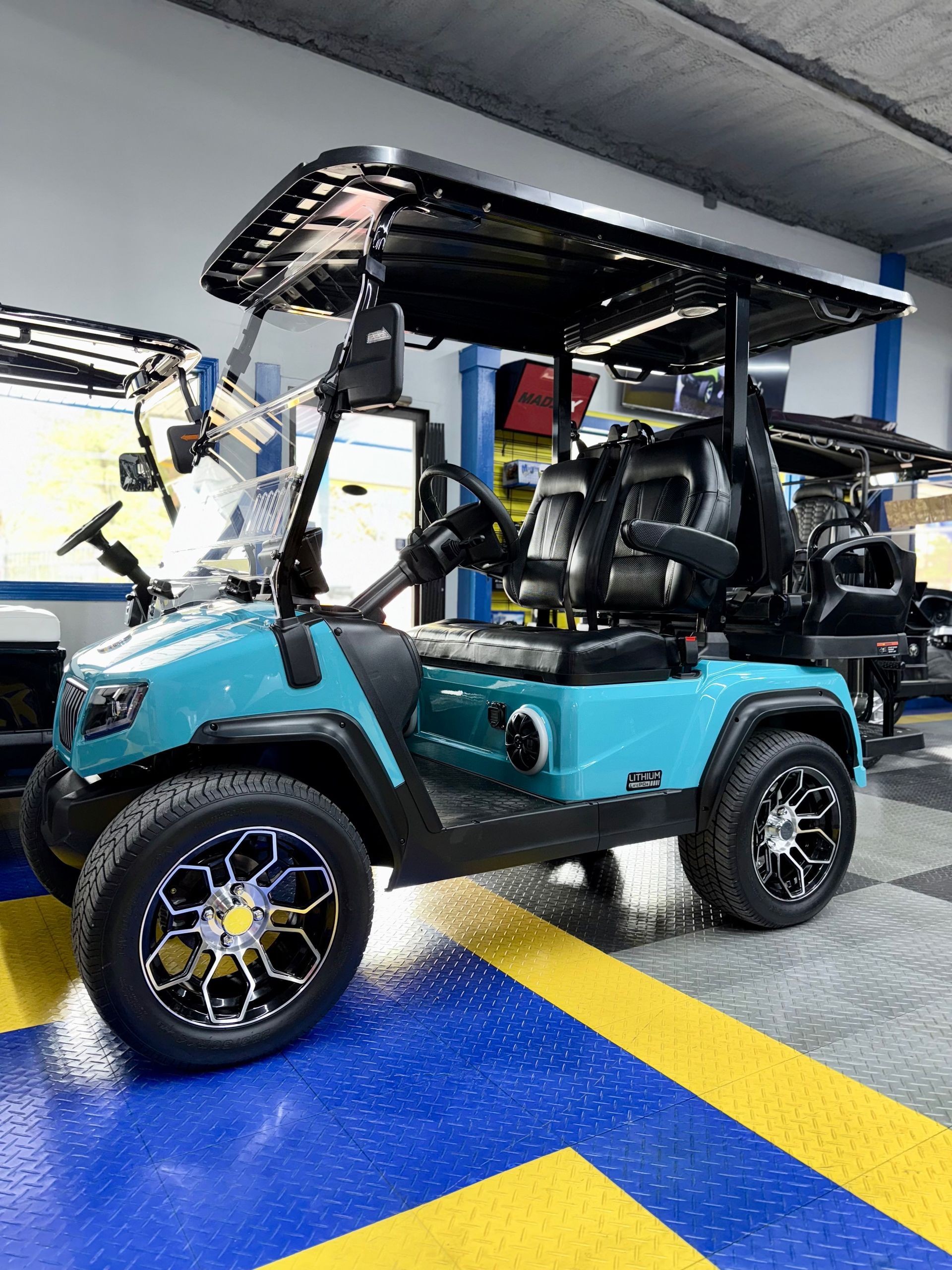 A blue golf cart is parked in a garage.