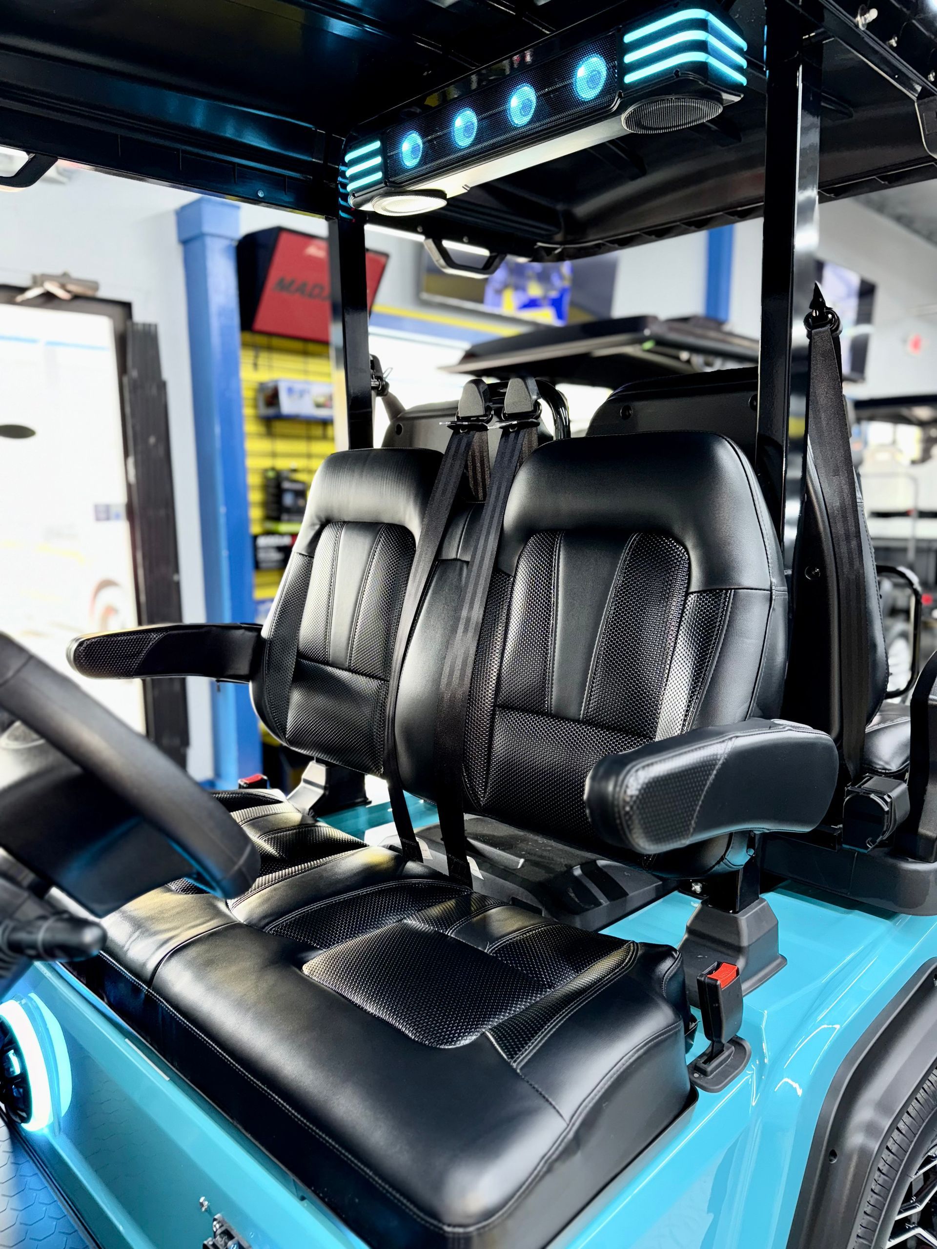 A blue golf cart with black seats is parked in a garage.