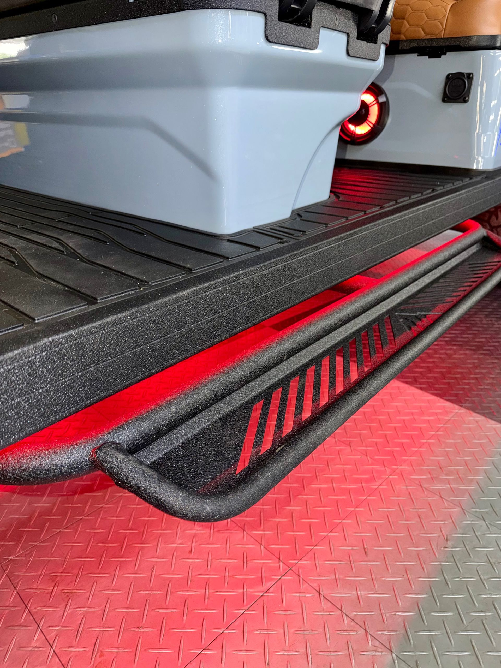 Red-lit 3D printer printing a gray part on a textured build plate