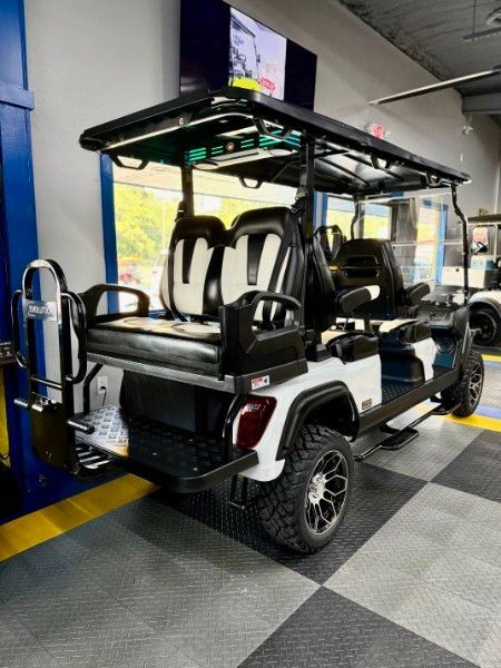 A white and black golf cart is parked in a garage.