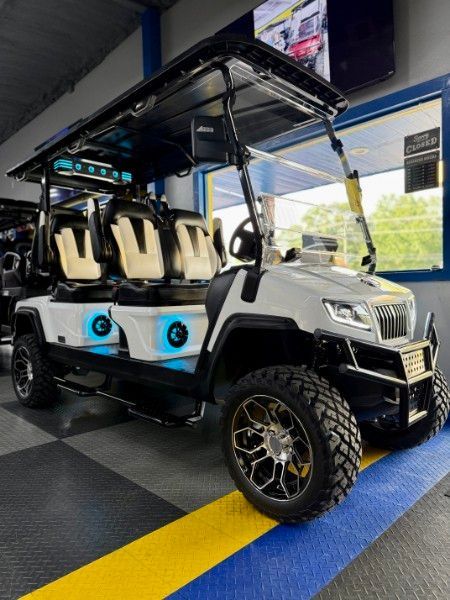 A white golf cart is parked in a garage.