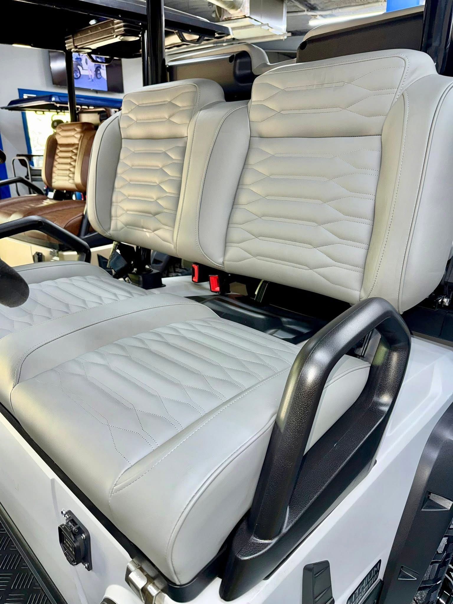 White padded stadium-style bench seats with black armrests in a vehicle or transport interior