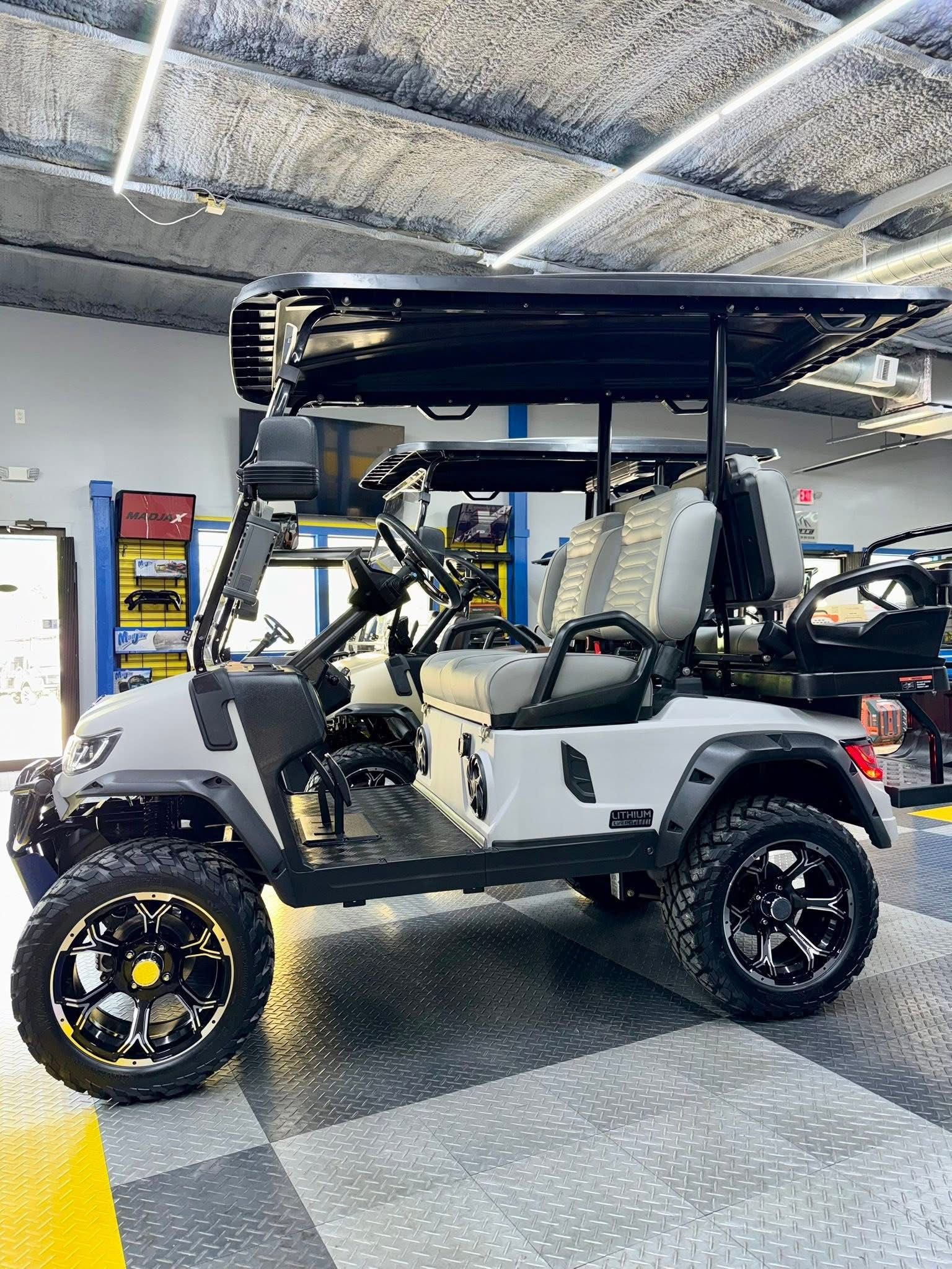 Gray lifted golf cart with black roof and off-road tires in a showroom